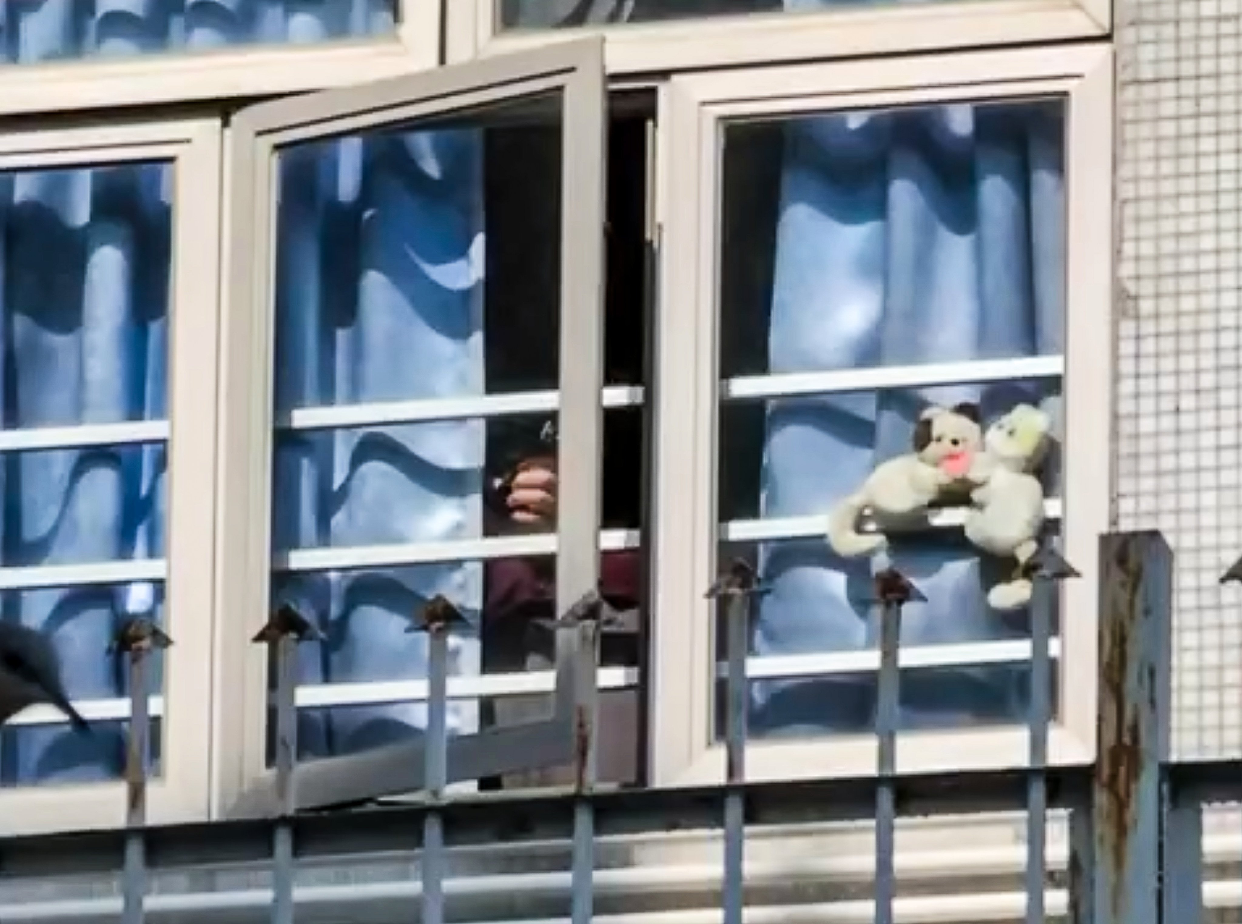 A video posted online shows a man peeking through the curtains of a window of a flat and holding what appears to be an airgun. Photo: Facebook