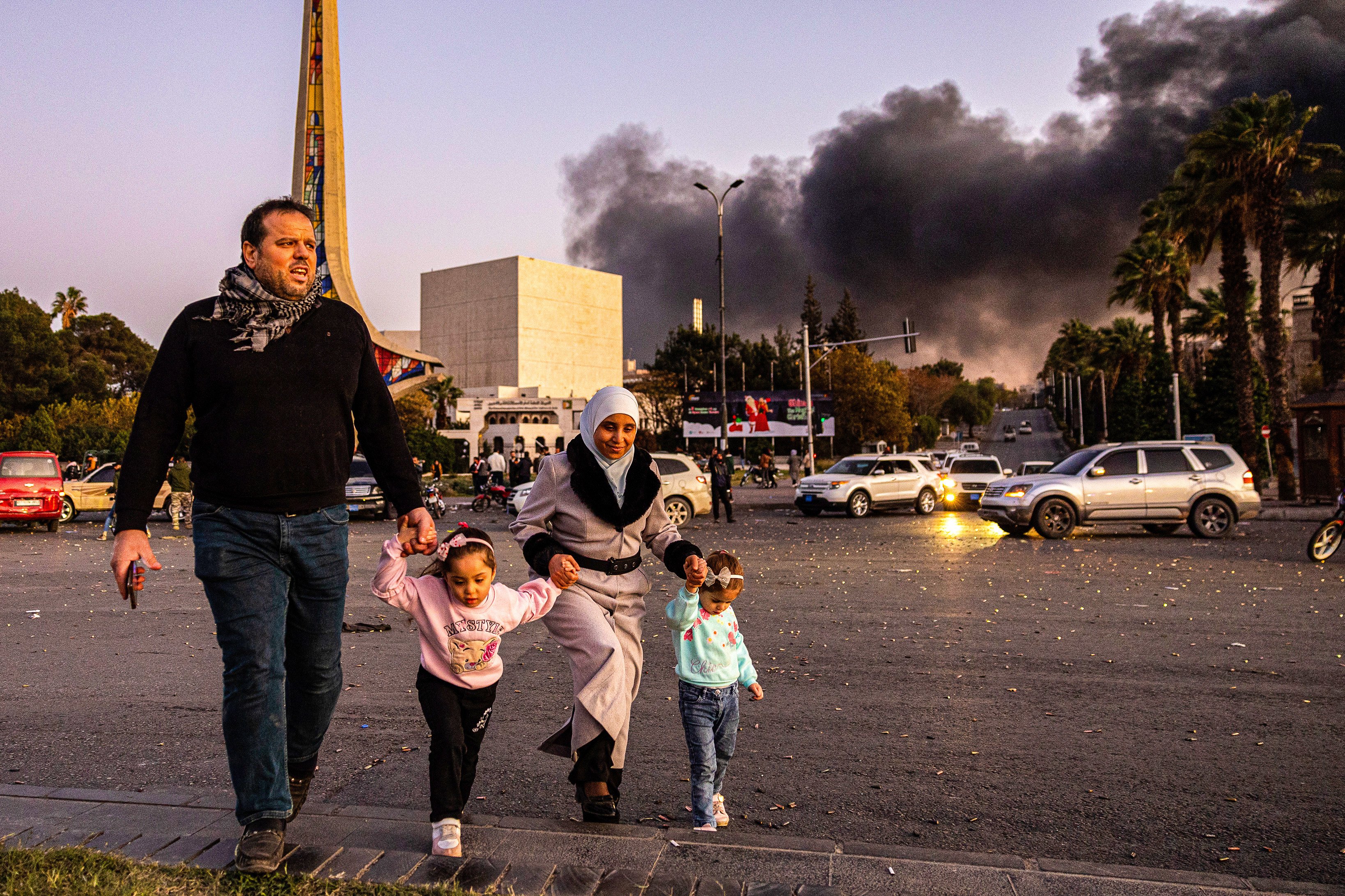 Smoke billows as people arrive to celebrate the fall of the Syrian government, in Damascus, Syria on Sunday. Photo: AP