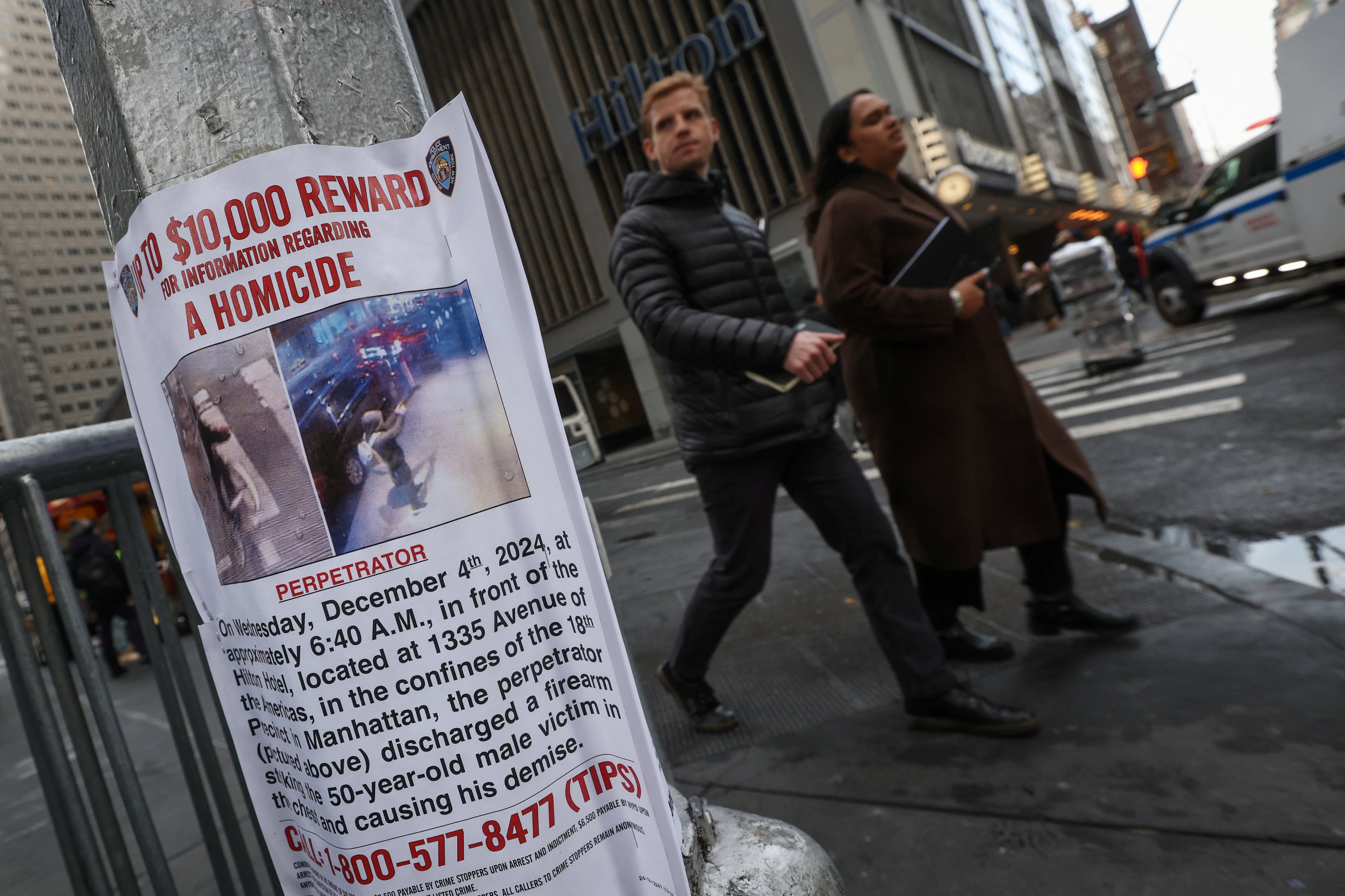 People walk past a poster outside the Hilton hotel near the scene where Brian Thompson, the CEO of UnitedHealthcare, was shot dead in midtown Manhattan, in New York, on December 5. Photo: Reuters