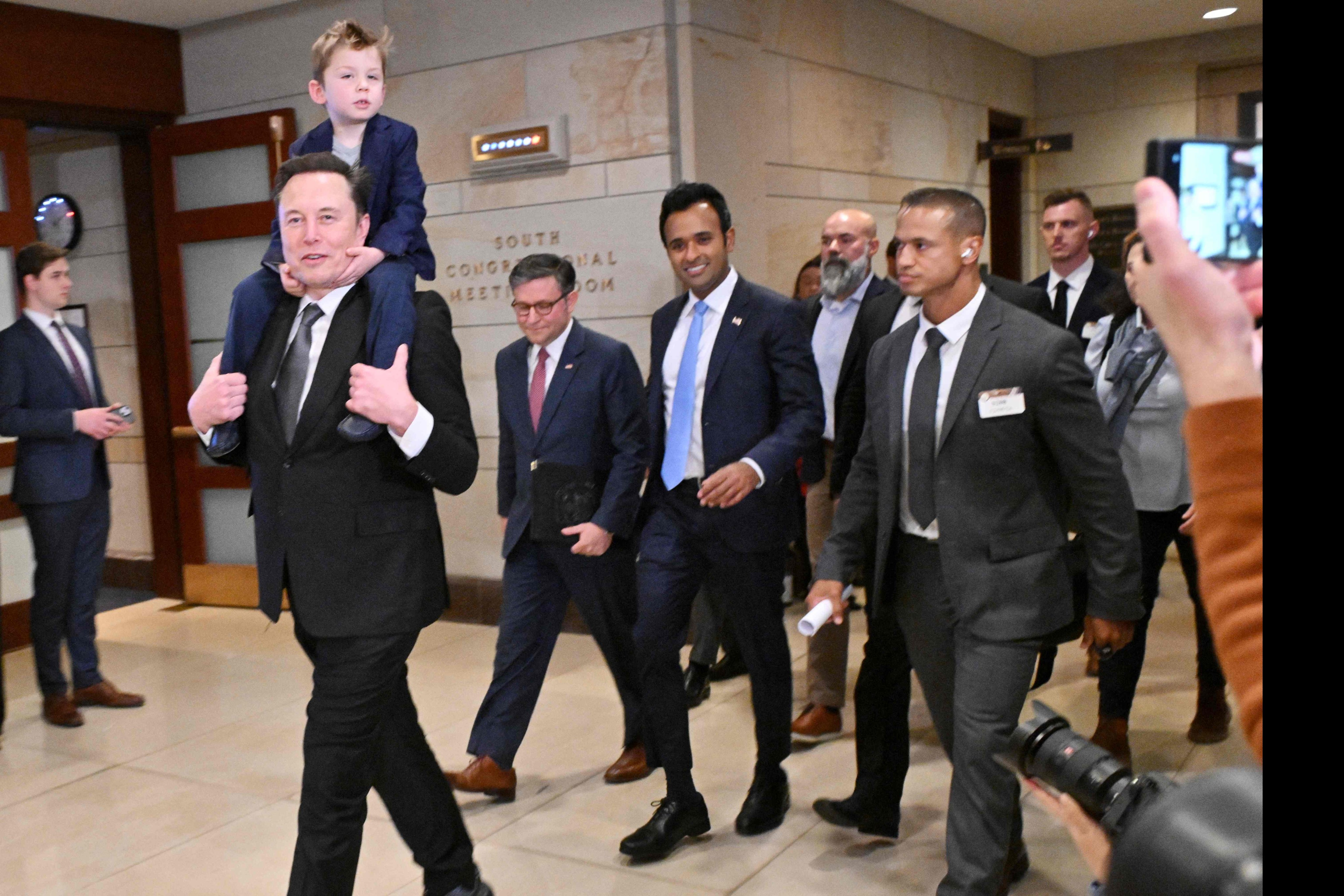 Tesla CEO Elon Musk, with son on his shoulders, is to co-chair the newly created Department of Government Efficiency with businessman Vivek Ramaswamy (in a blue tie). Both men seen before a meeting with Congress members at the US Capitol in Washington on December 5. Photo: AFP