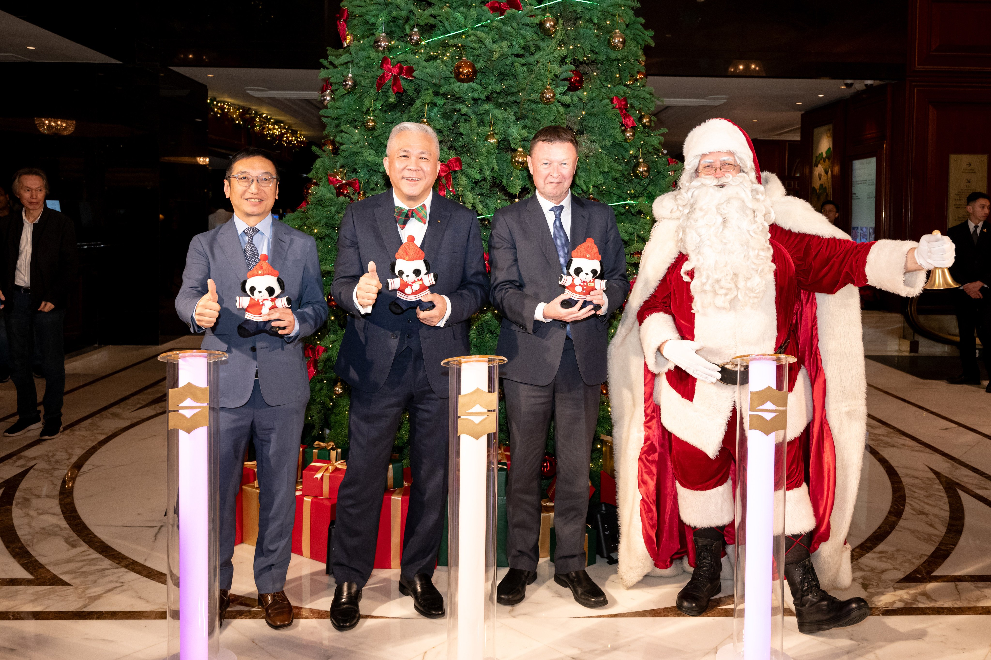 (From left) Paul Wong, SCMP’s general counsel and company secretary, Christopher Chia, Kowloon Shangri-la’s general manager, and Jim Gould, RTHK’s adviser of English programme service, hold Edward Panda toy mascots alongside Santa Claus at the hotel’s Christmas tree lighting ceremony. Photo: Handout