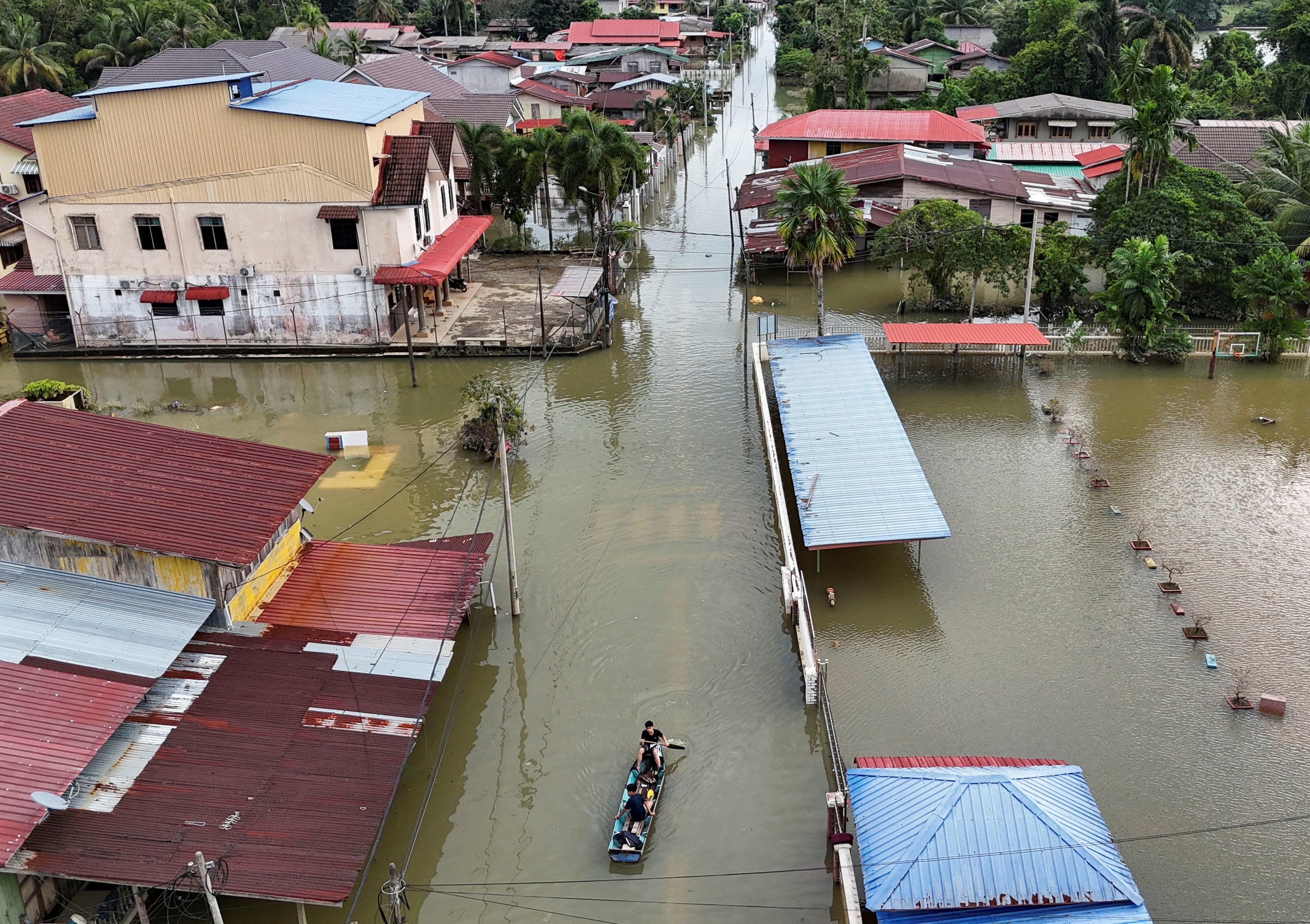 Residents ride a boat in a flooded area in Rantau Panjang, Malaysia’s Kelantan state, on December 3. Photo: Reuters