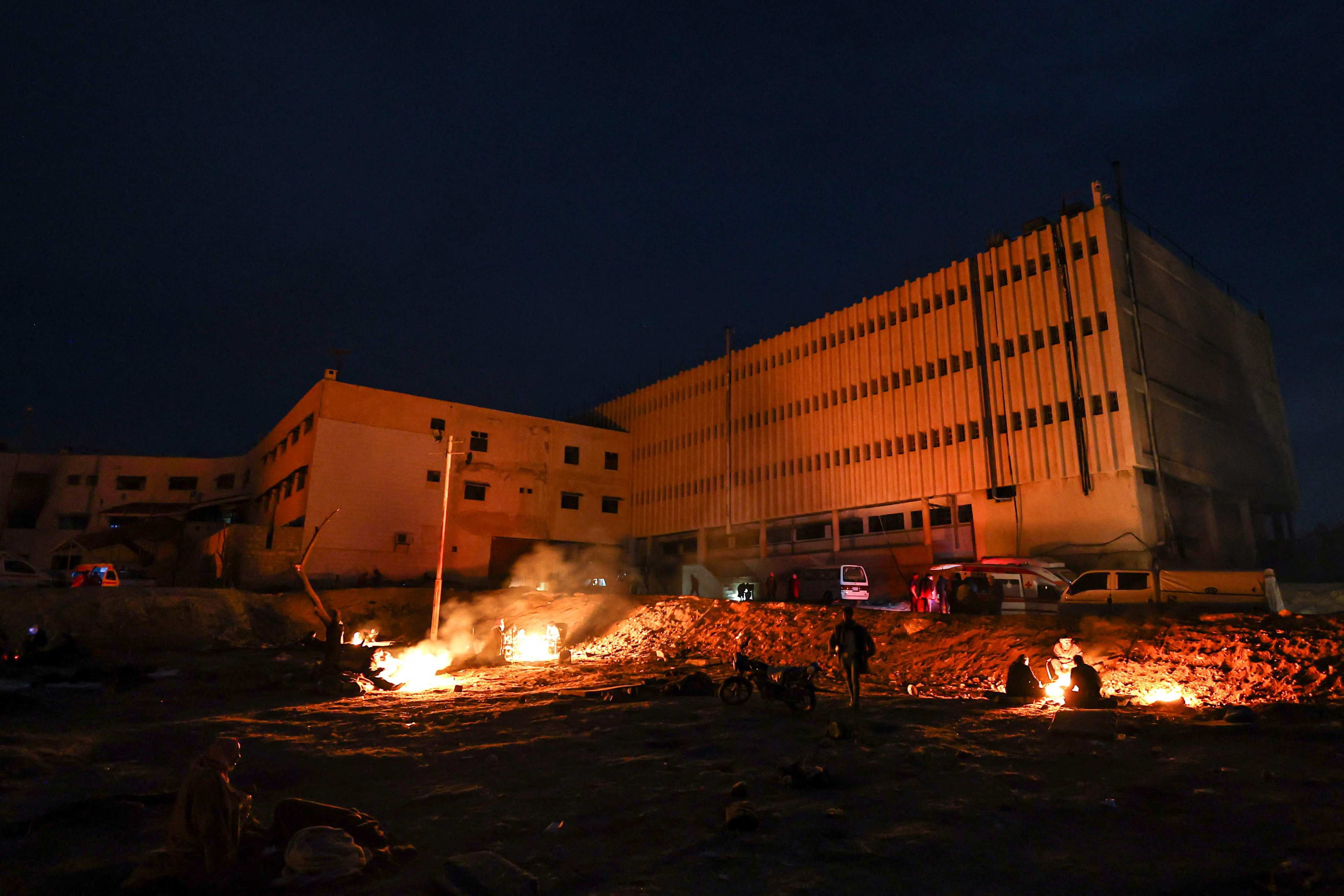 People keep warm around a bonfire outside the Saydnaya prison in Damascus on December 11. Photo: AFP