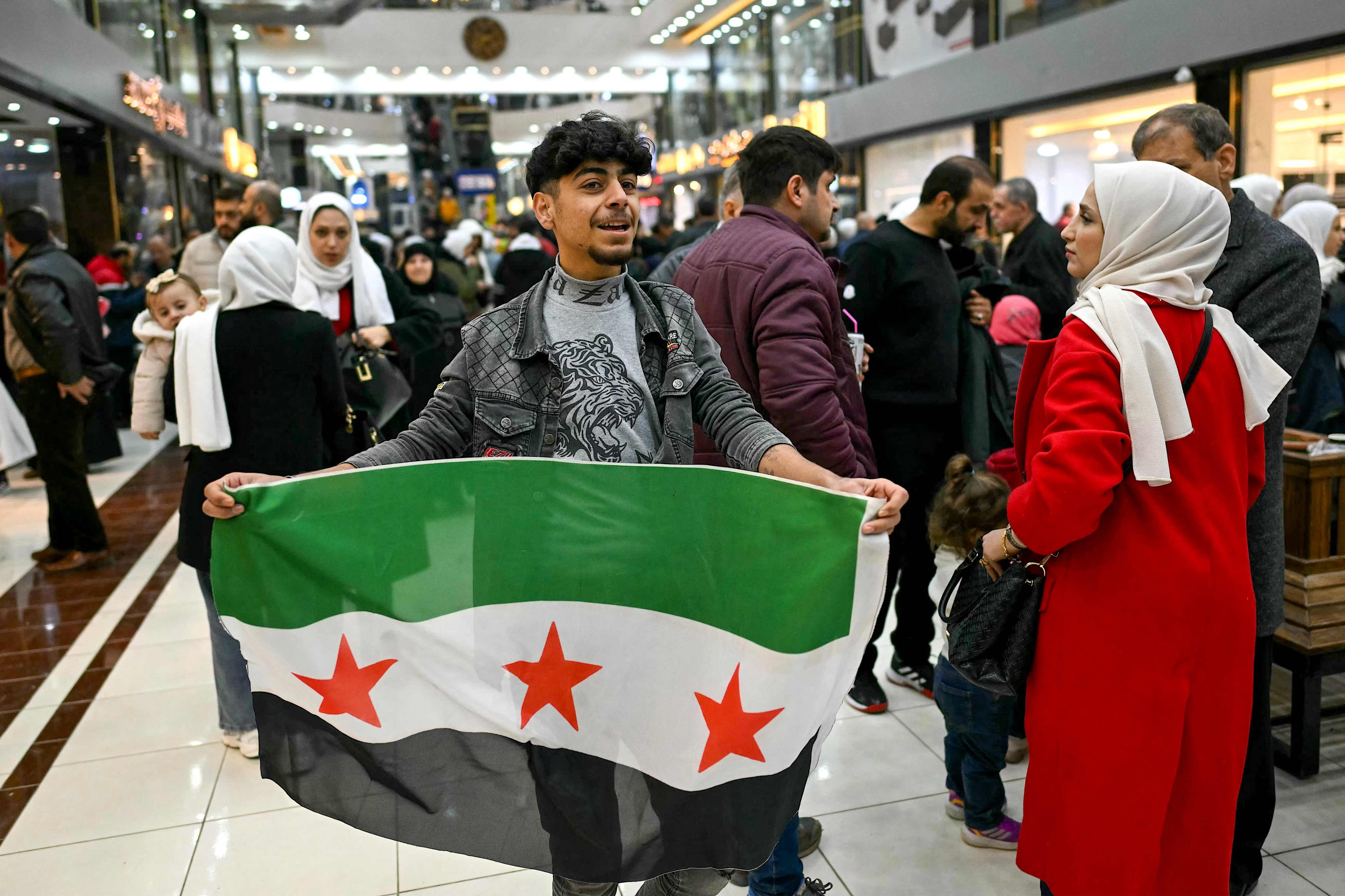 A youth holds a Syrian independence-era flag inside a shopping mall in the town of al-Dana, near Sarmada, in the northern Syrian province of Idlib, on Friday. Photo: AFP