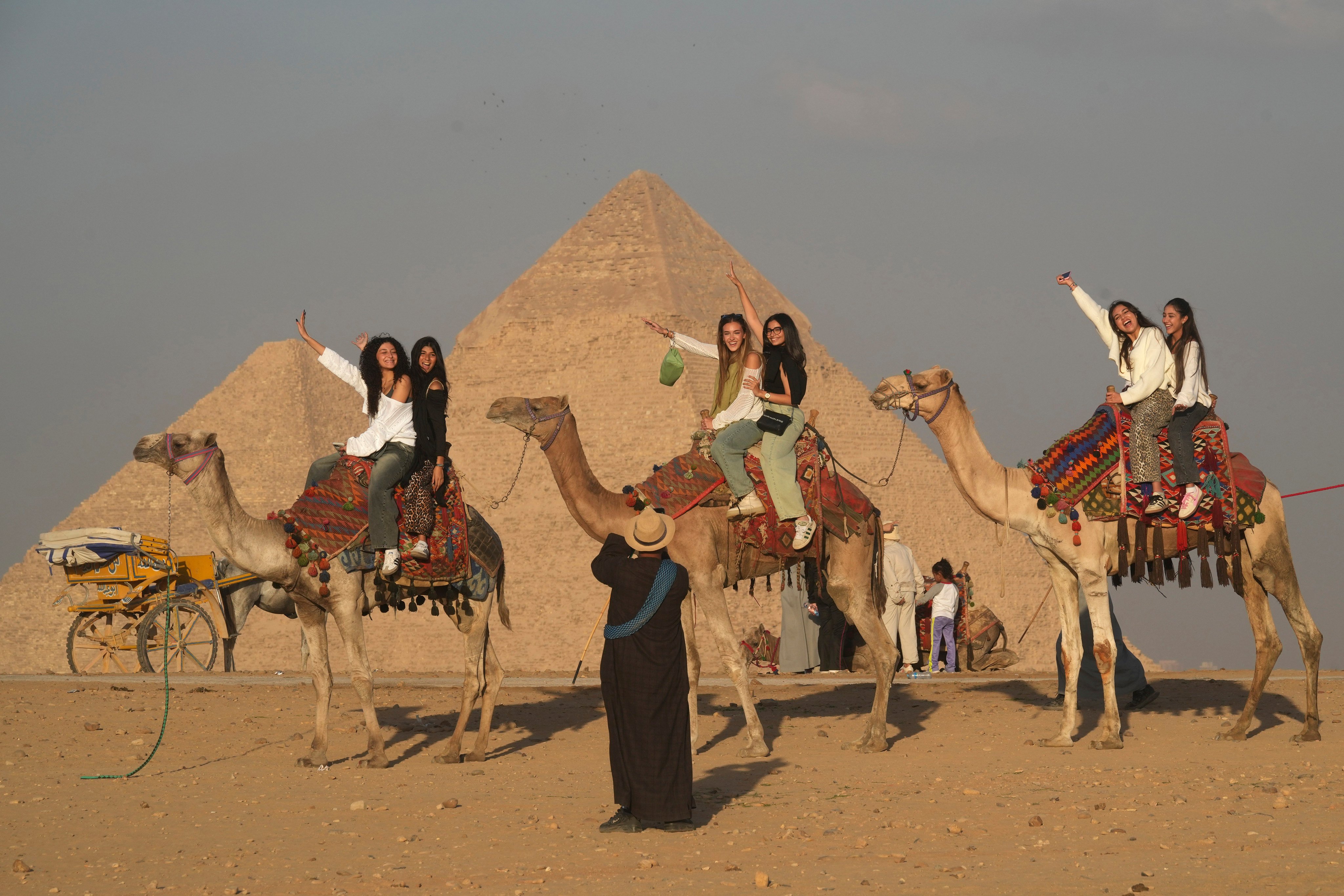 Visitors on camels pose for pictures with the Pyramids. Photo: AP