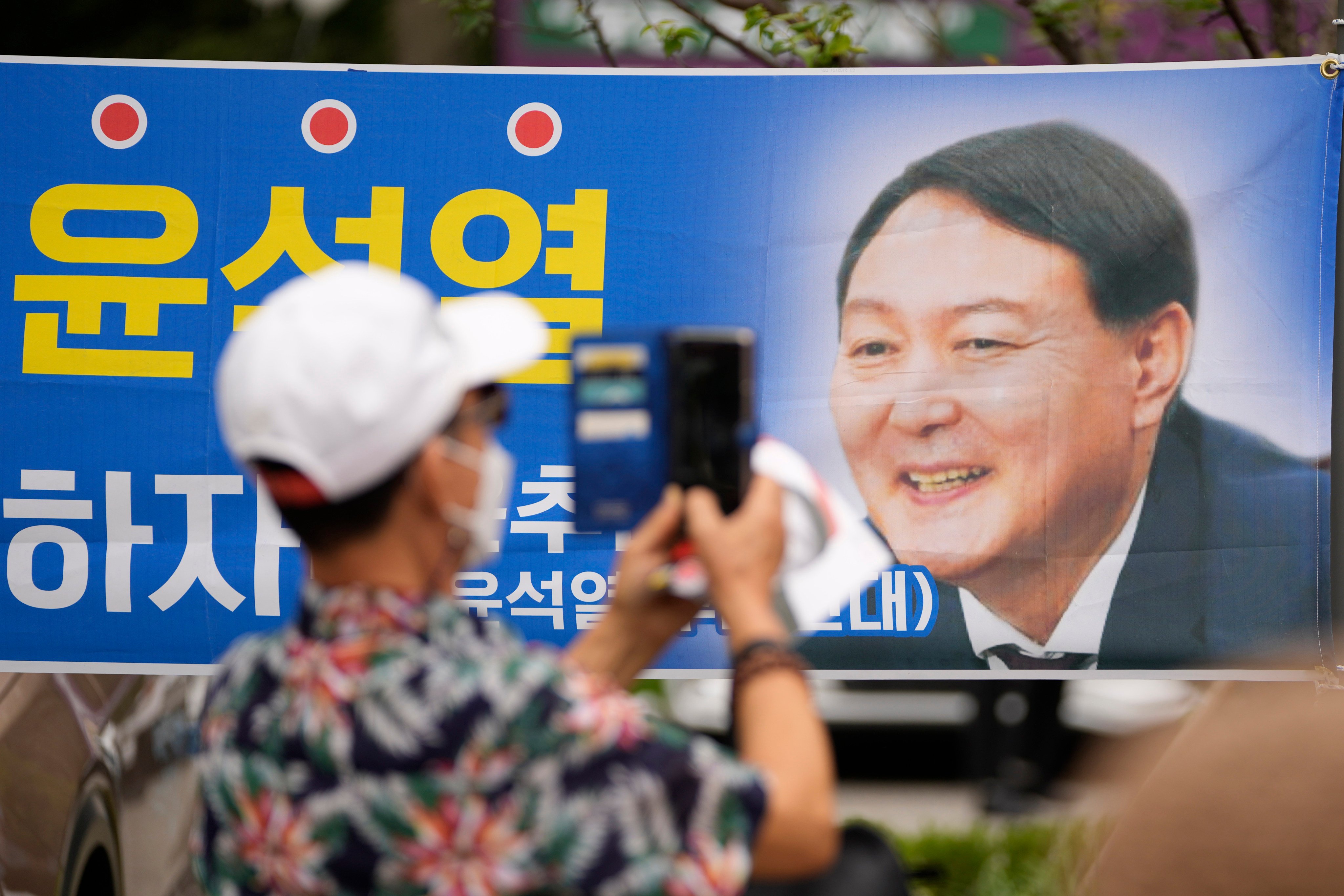 A supporter takes a photo of a banner featuring Yoon Suk-yeol in June 2021, the month he launched his bid to run for South Korea’s presidency. Photo: AP