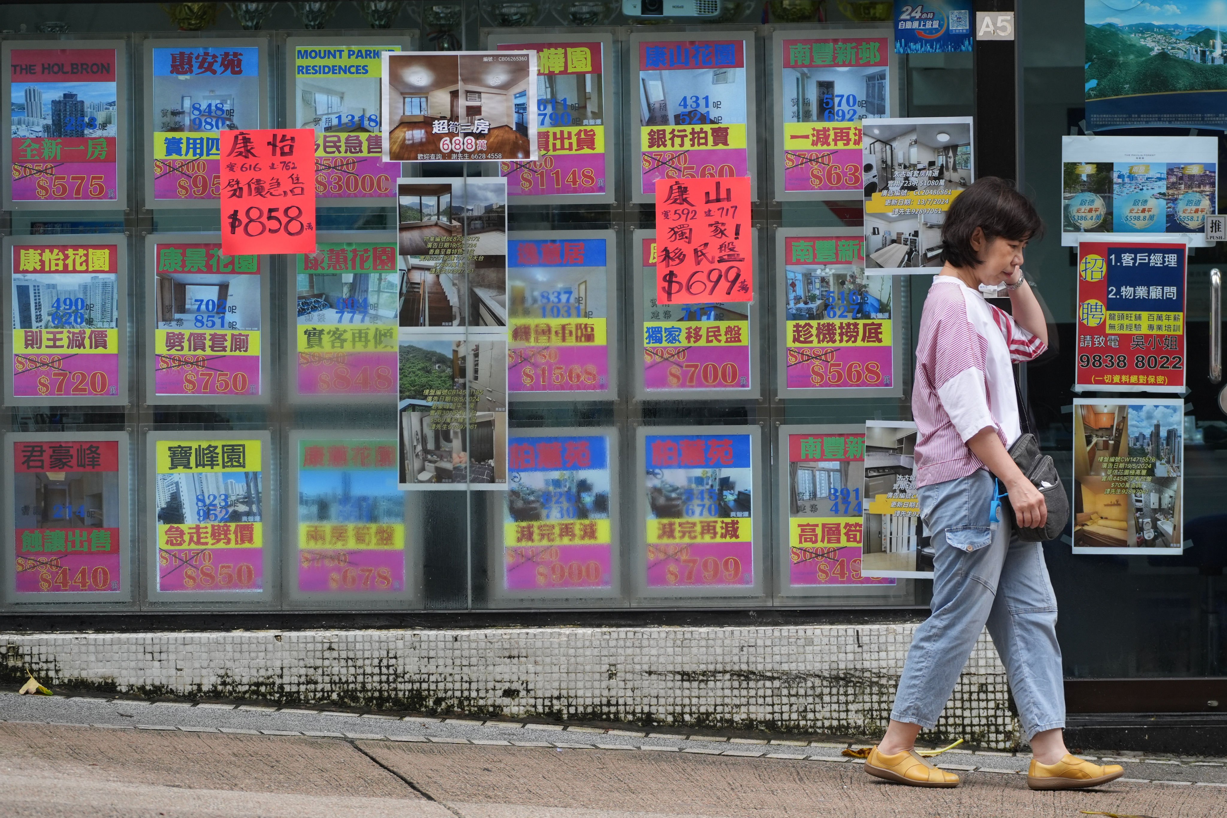 A woman walks past a real estate agency in Tai Koo featuring properties where prices have been slashed, on July 24. Photo: Eugene Lee
