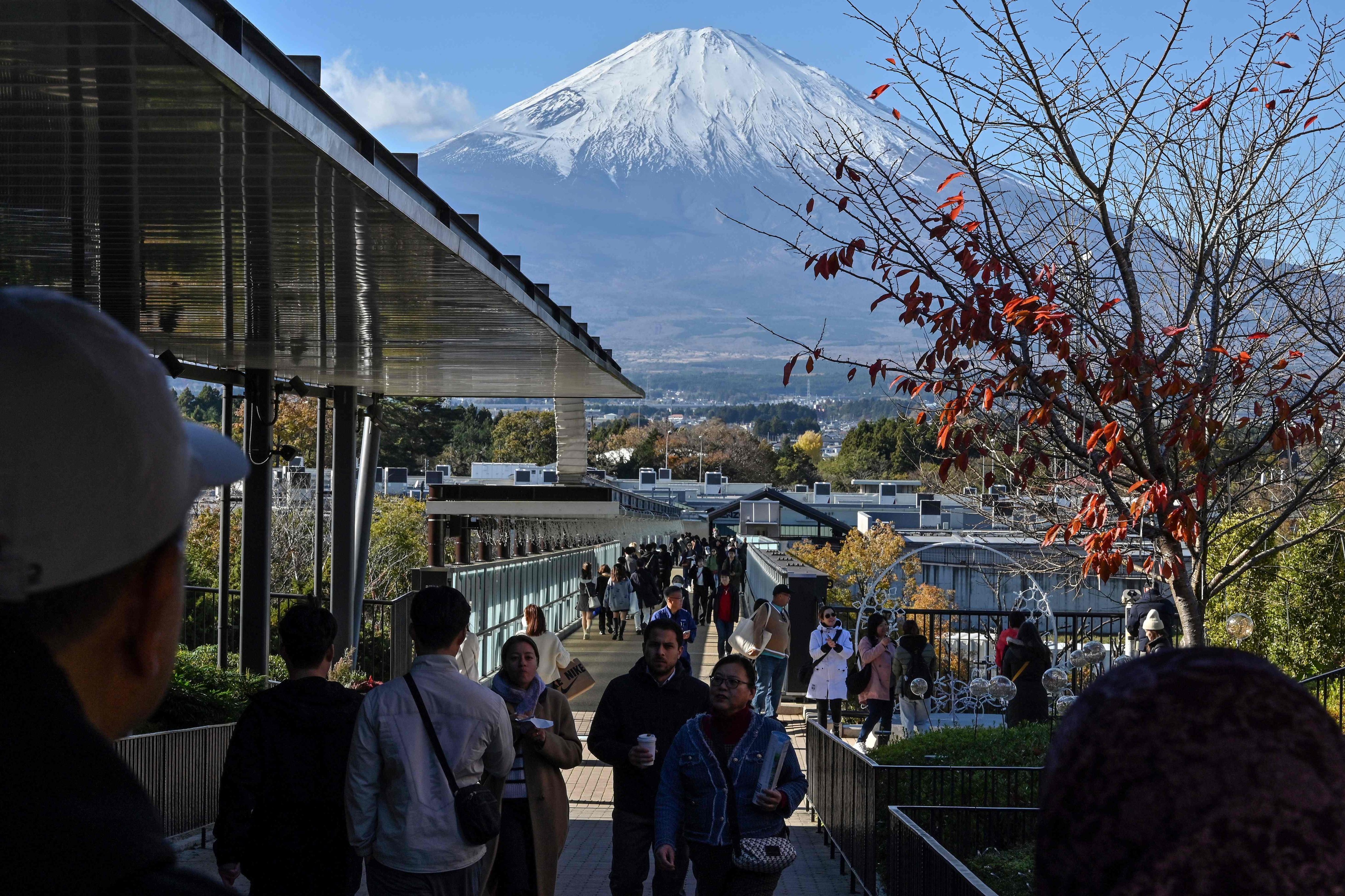 Mount Fuji is pictured in the background as people walk around a popular outlet shopping centre in the city of Gotemba, Shizuoka prefecture, on November 28. Photo: AFP