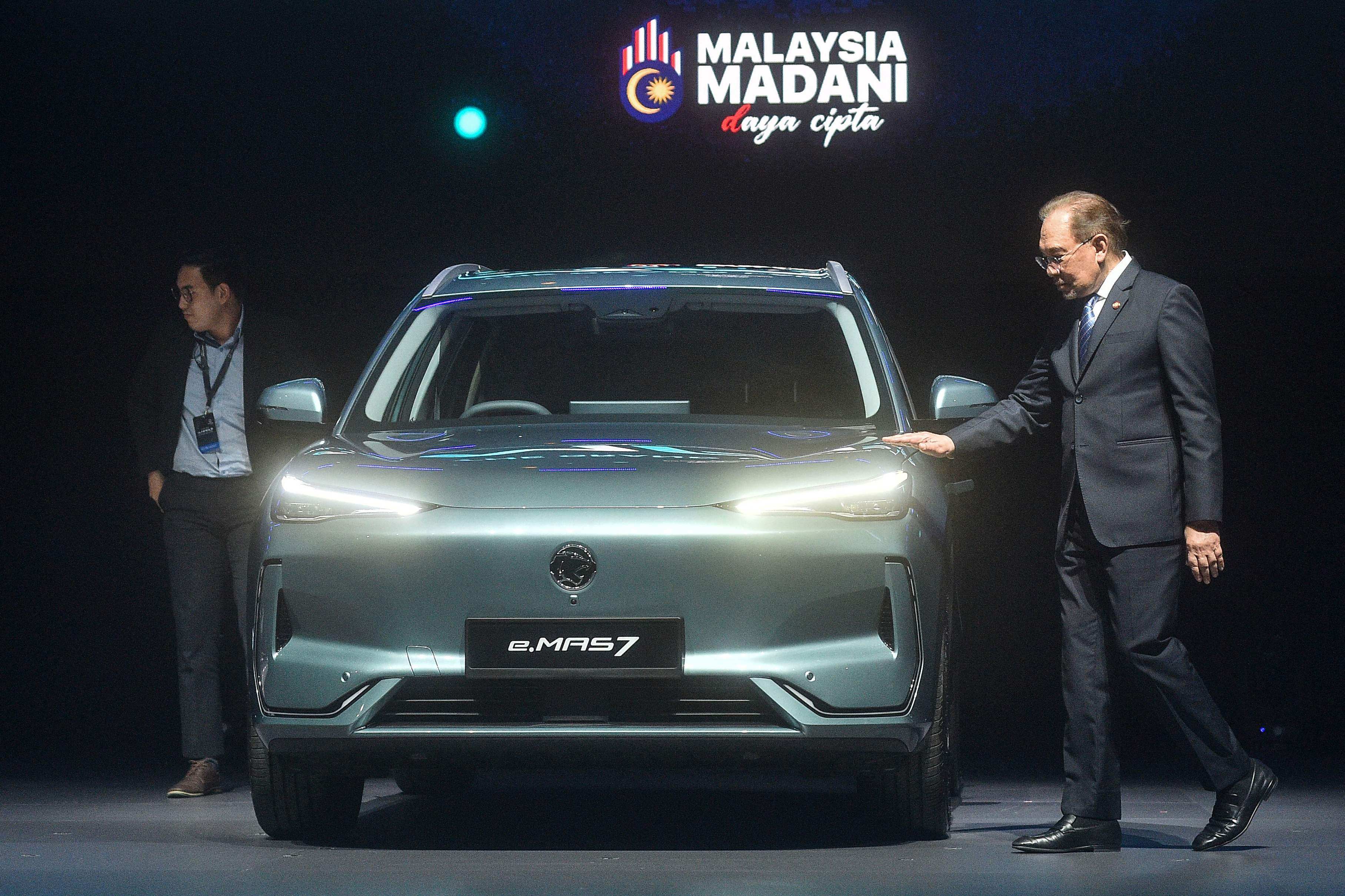 Malaysia’s Prime Minister Anwar Ibrahim touches the first locally produced electric vehicle (EV), the e.MAS 7, during its launch event in Kuala Lumpur on December 16/ Photo: AFP