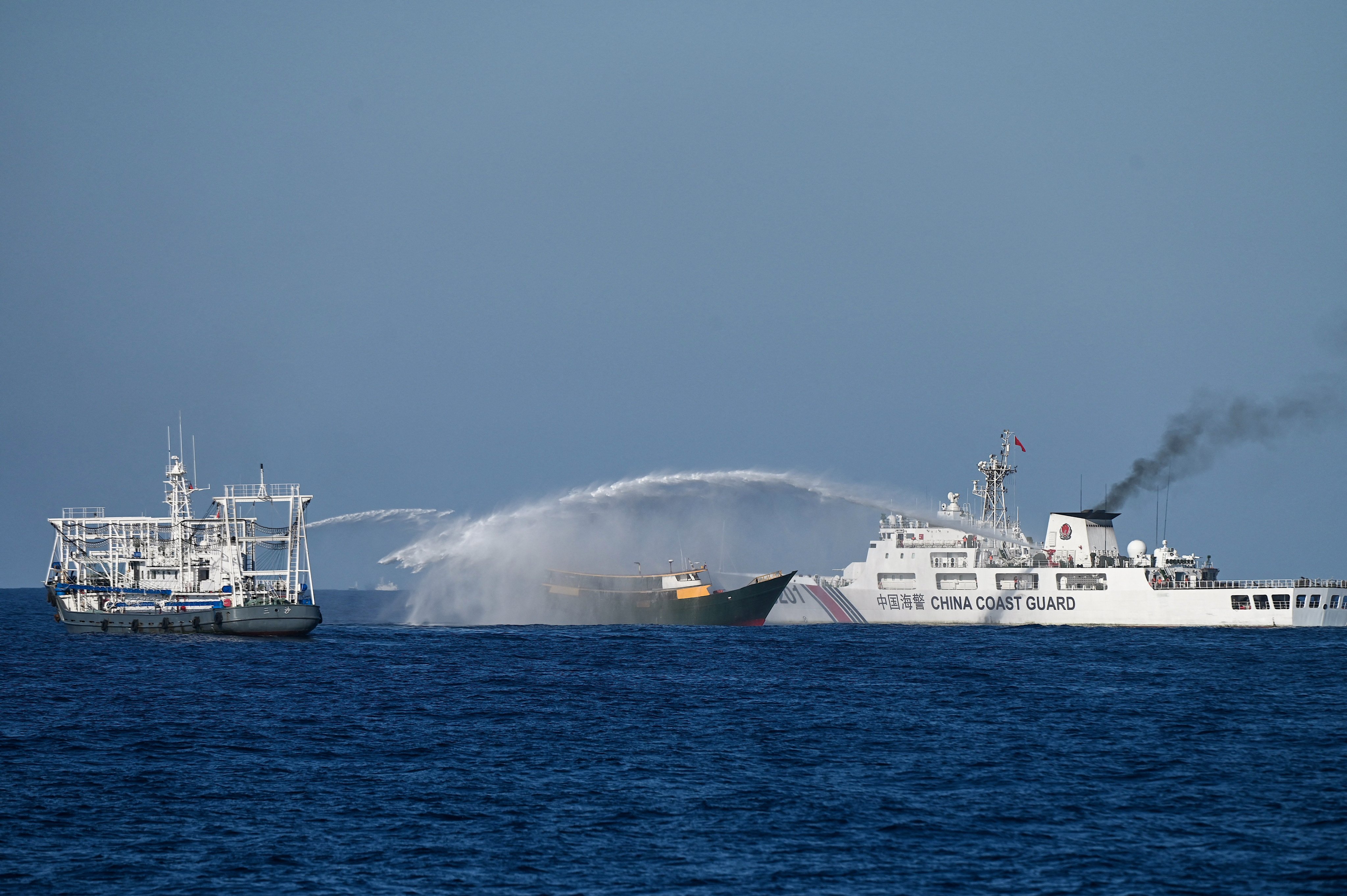 A Chinese coastguard vessel, right, fires a water cannon on a Philippine fisheing vessel near a disputed shoal in the South China Sea on March 5. Photo: AFP