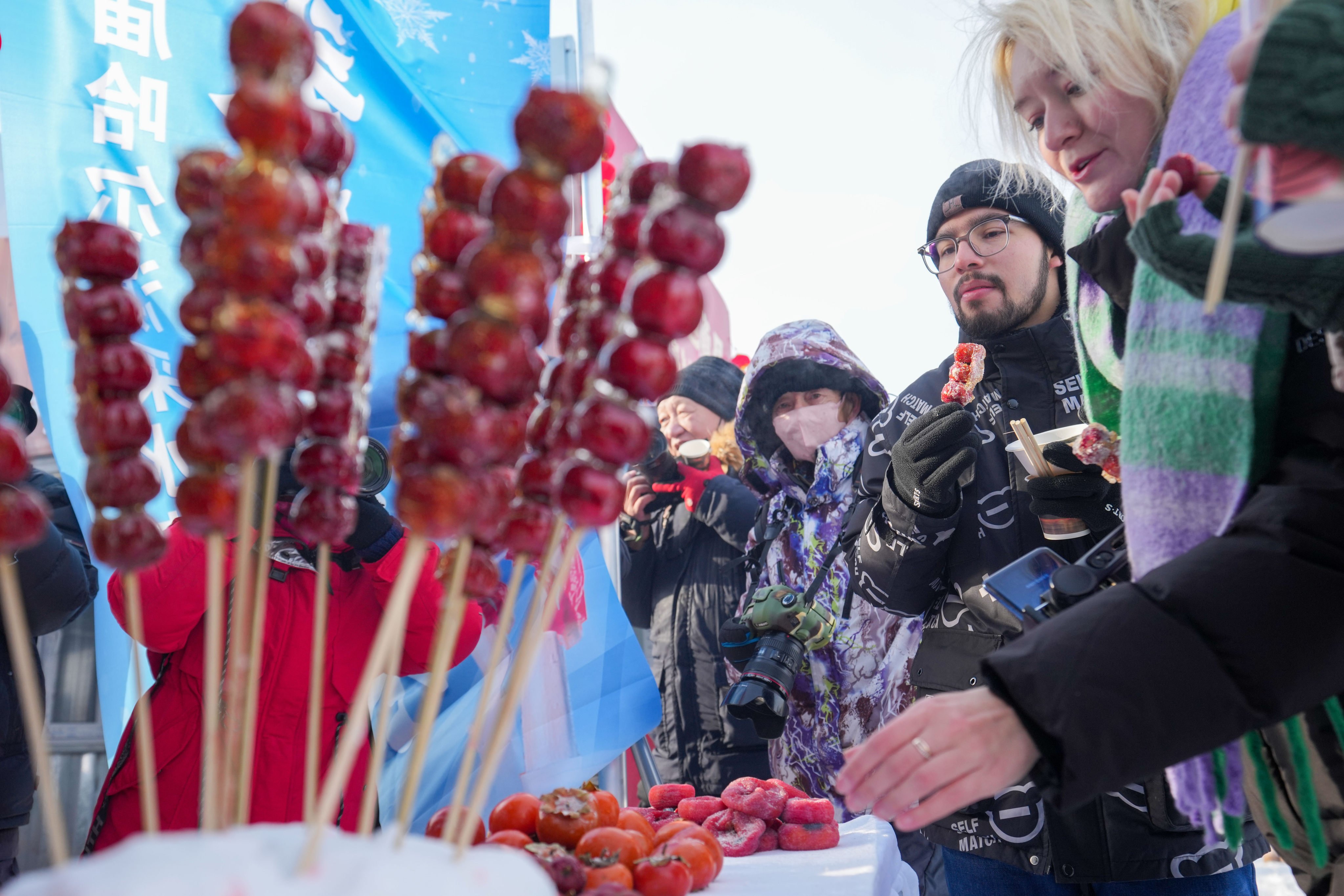 Foreign tourists try snacks during an ice-collecting festival in Harbin. Photo: Xinhua