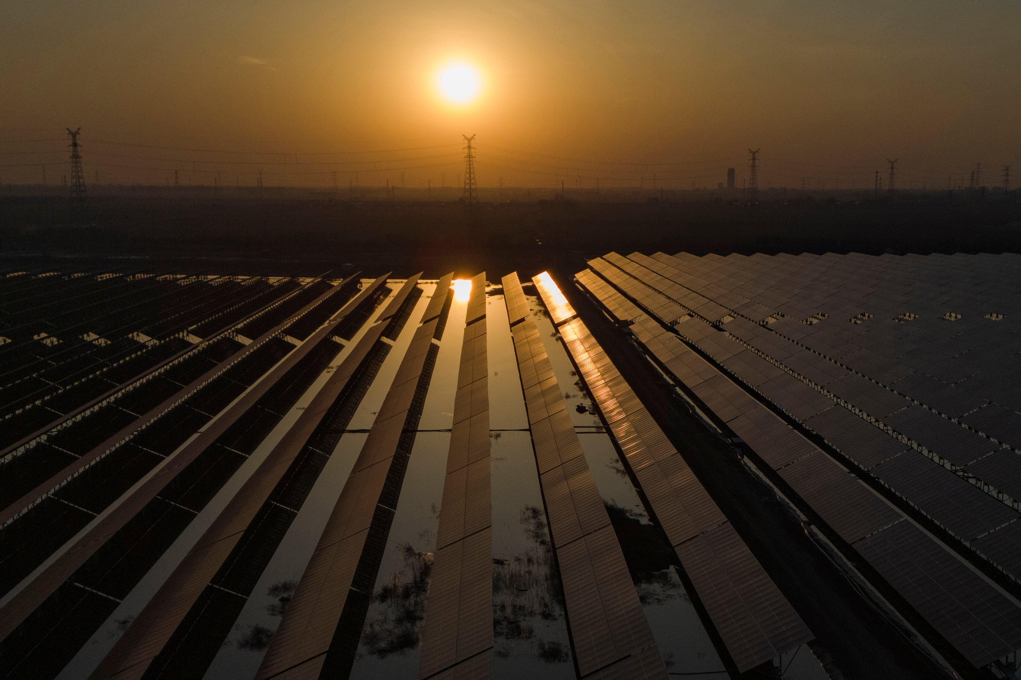 The sun sets over electric pylons beside a solar farm near Weifang, Shandong province, in March. Photo: AP