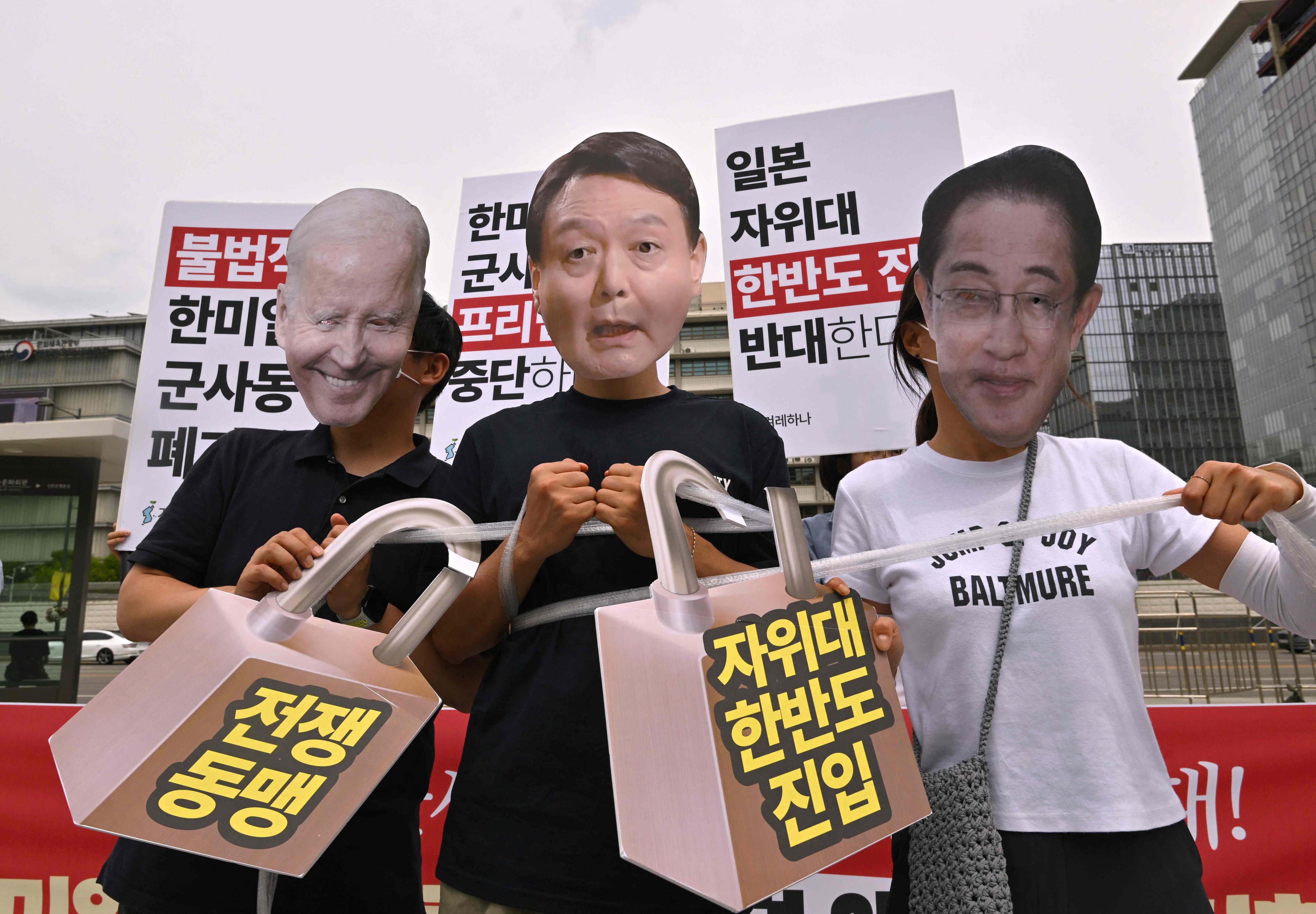 South Korean protesters wear masks of President Yoon Suk-yeol (centre),  US President Joe Biden and then Japanese prime minister Fumio Kishida as they demonstrate against a trilateral military exercise in front of the US embassy in Seoul on June 27. Photo: AFP