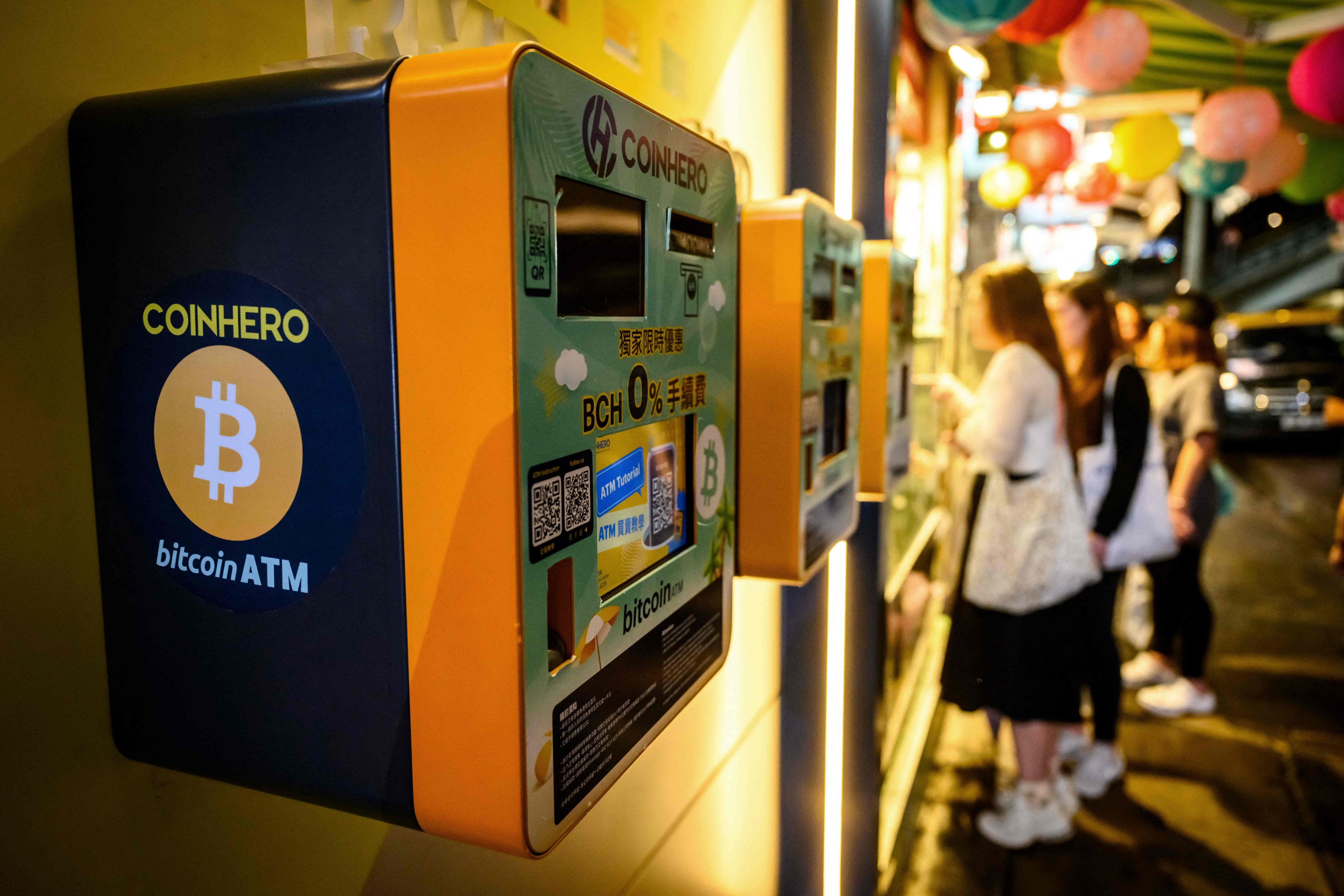 People stand next to bitcoin ATMs outside a cryptocurrency exchange in Hong Kong on November 14. Photo: AFP