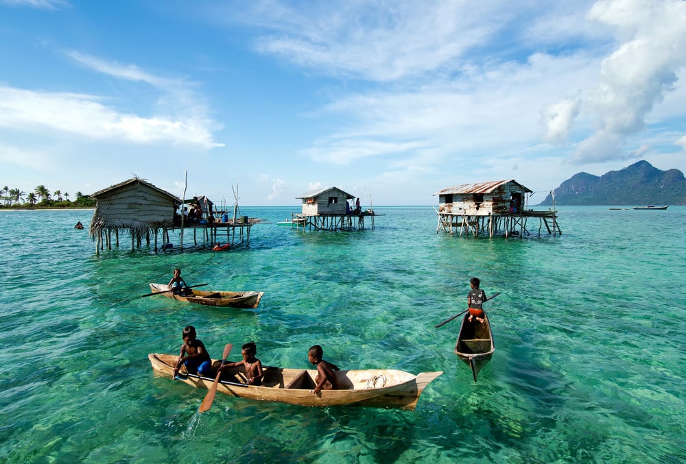 Young Bajau Laut children paddling a boat near stilted houses off the coast of Borneo near Tun Sakaran Marine Park. Photo: Shutterstock