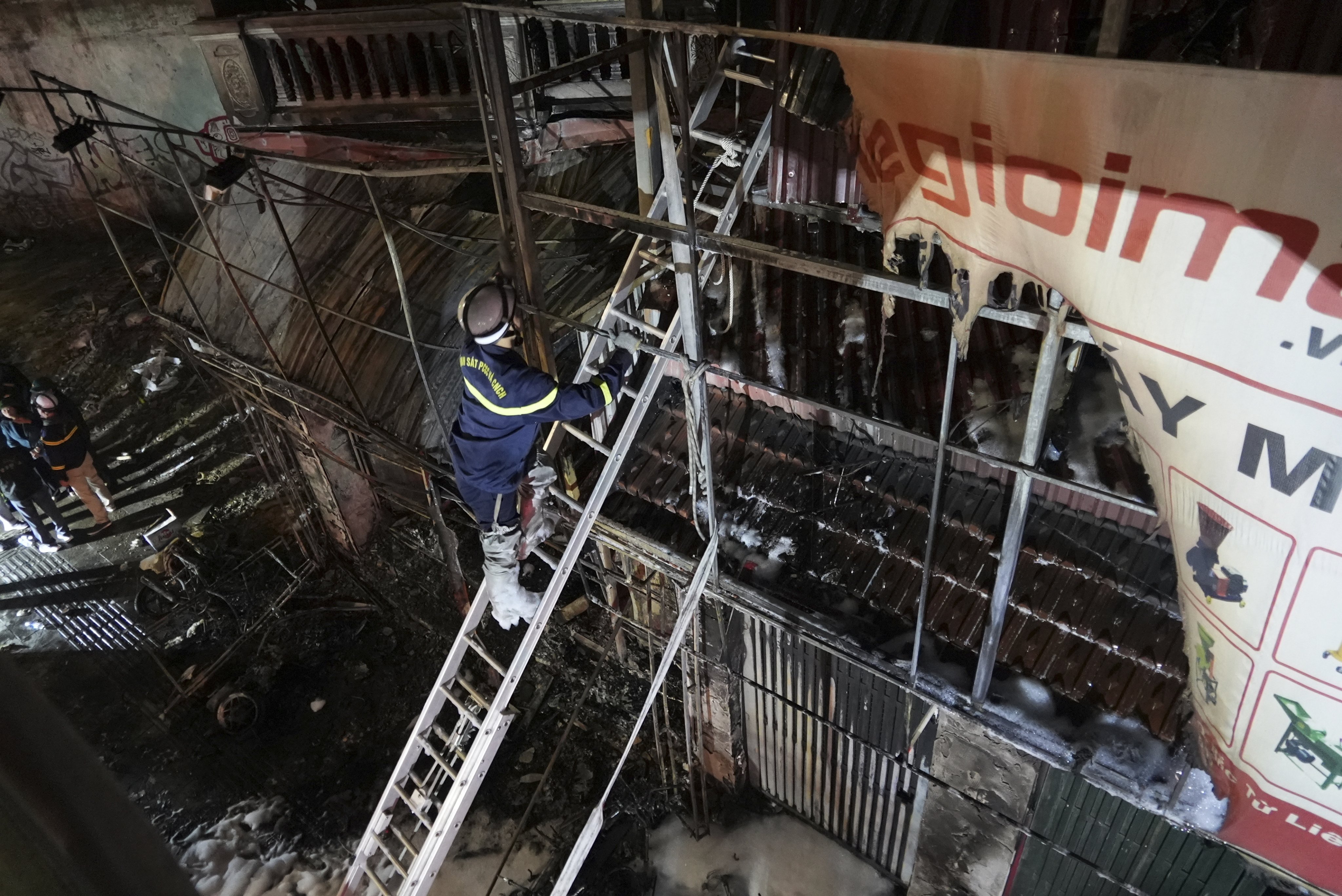 Firefighters inspect a building burned down by a blaze in Hanoi, Vietnam, on Thursday. Photo: AP