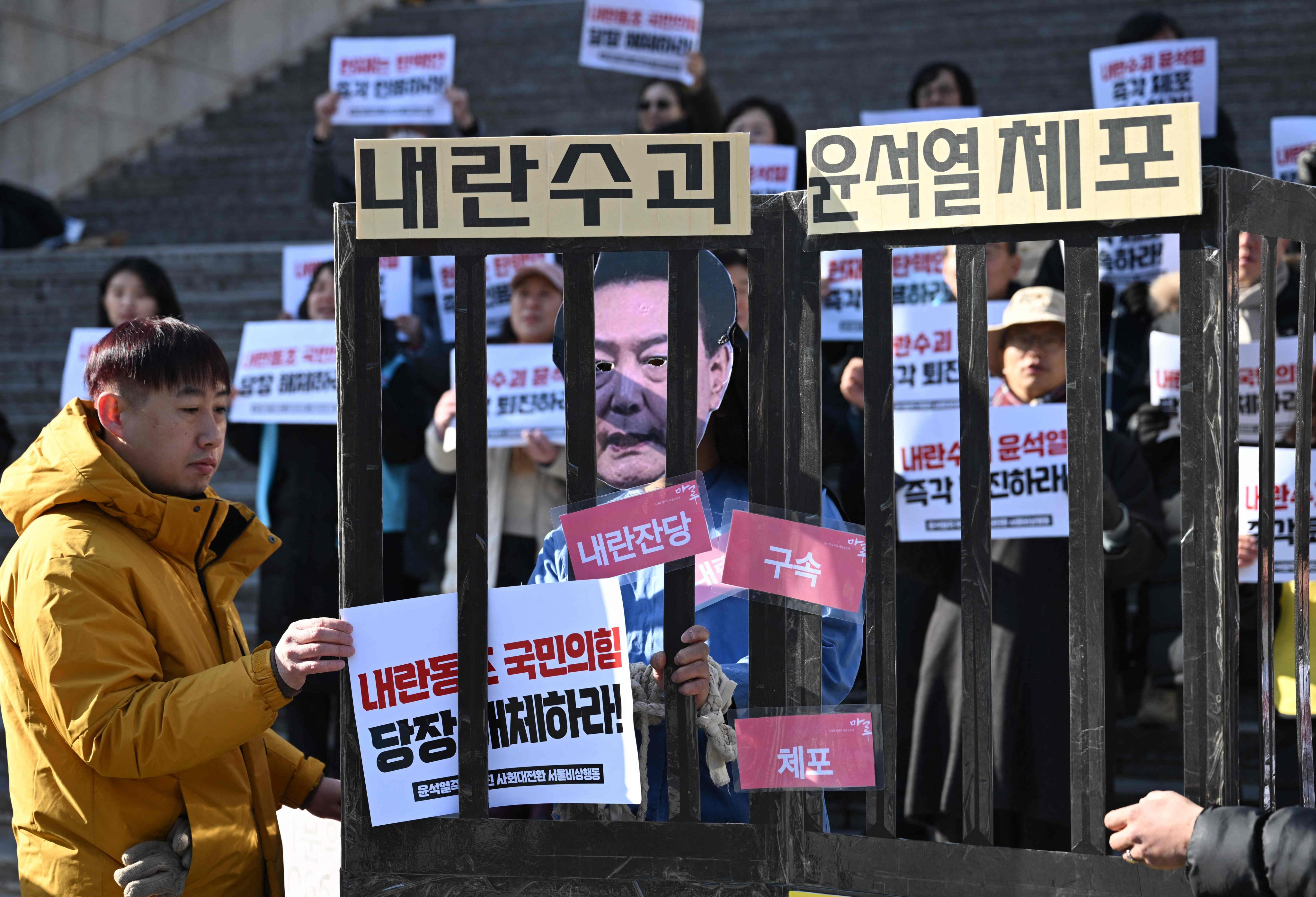 A protester wearing a mask of impeached South Korea President Yoon Suk-yeol performs in a mock prison during a demonstration calling for Yoon’s ouster in Seoul on December 19. Photo: AFP