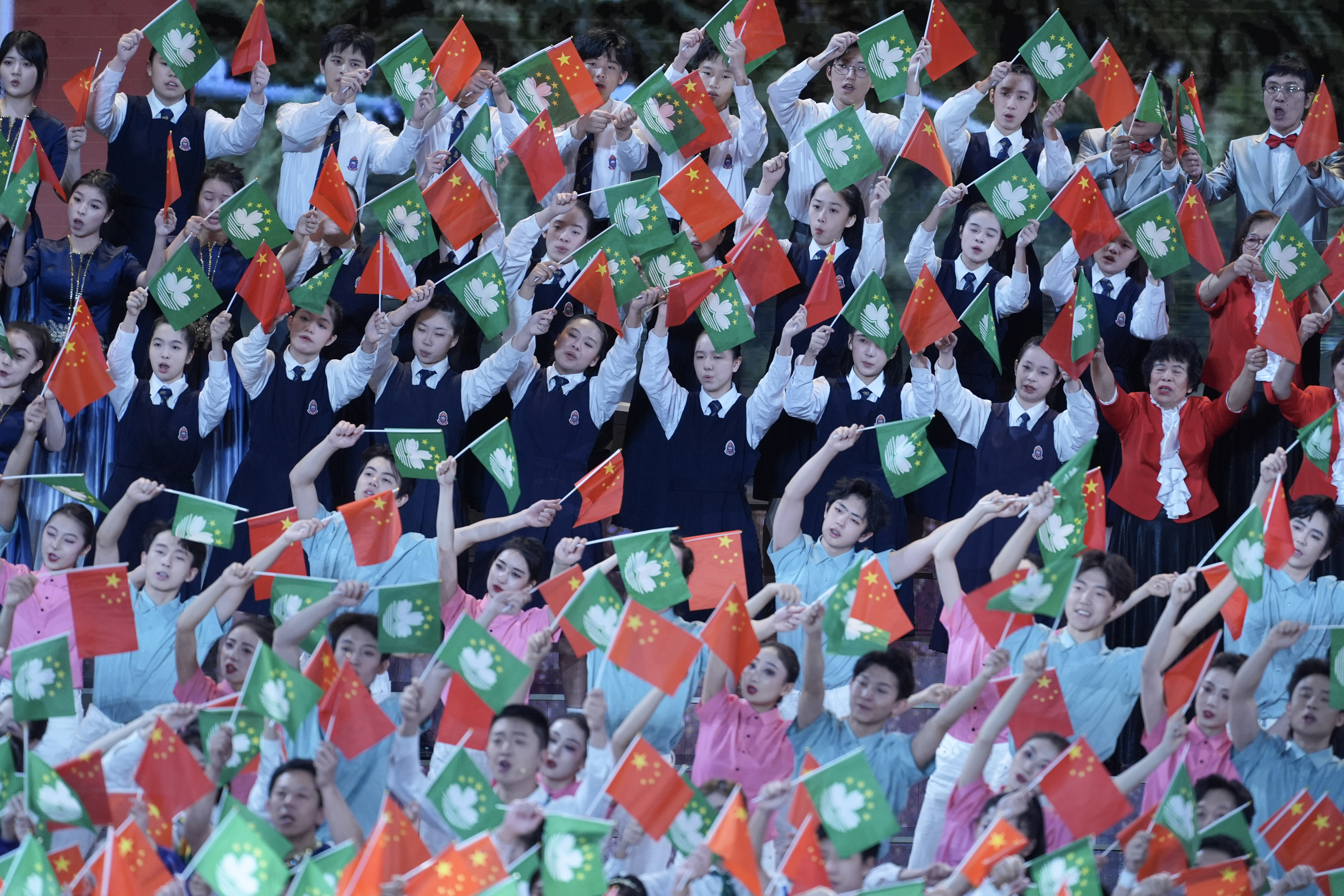 Performers wave Chinese and Macau  flags at a celebration of the 25th anniversary of the city’s return to Chinese administration. Photo: SCMP / Eugene Lee