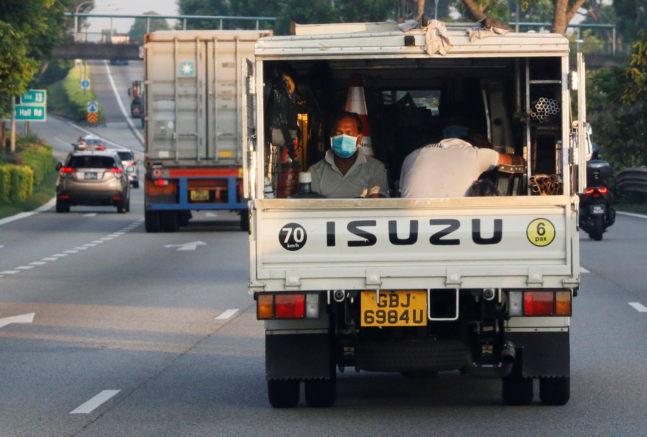 Migrant workers sit in the back of a truck in Singapore. Photo: Reuters