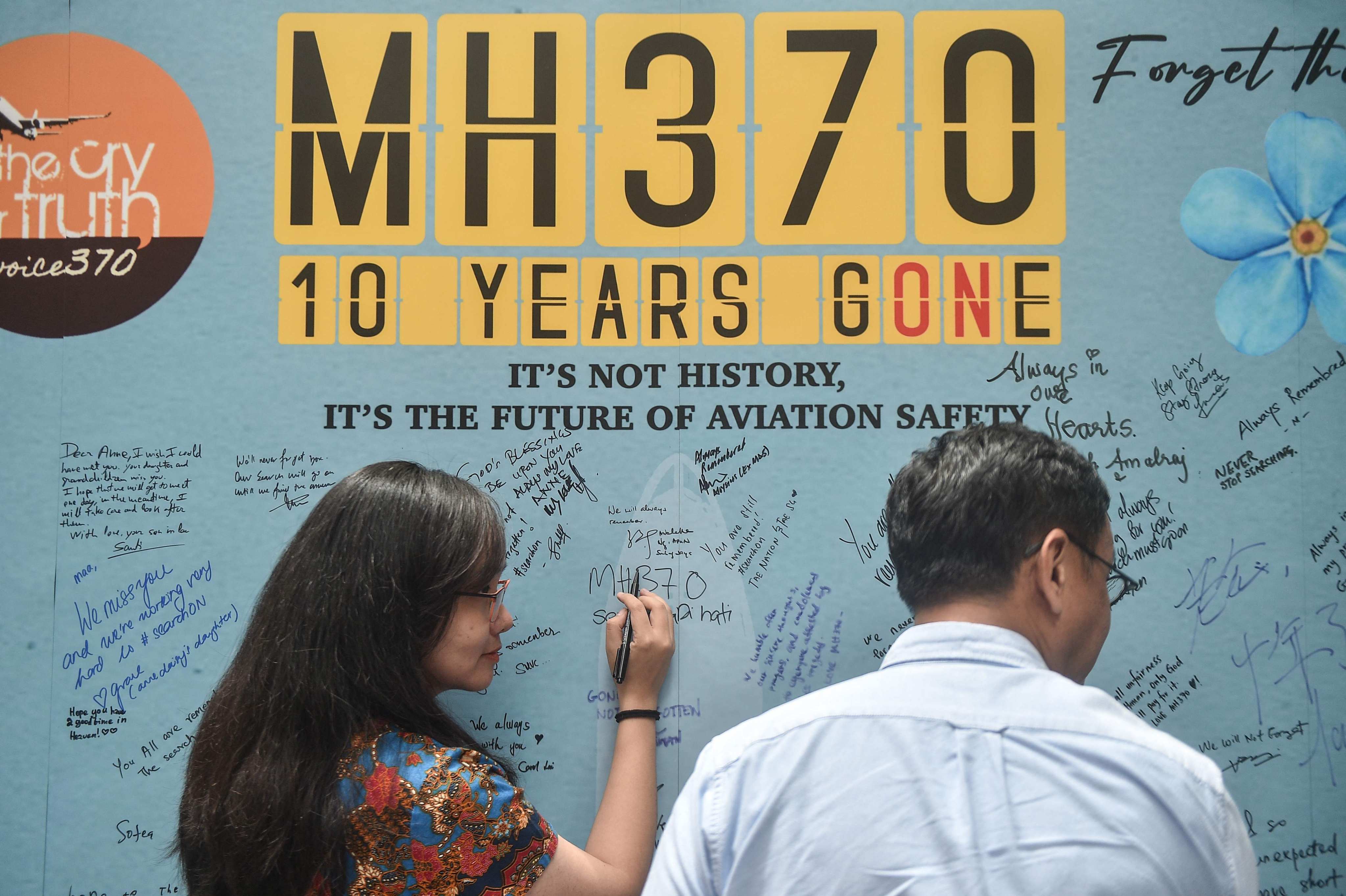 A woman writes a message at an event to mark the 10th year since the Malaysia Airlines flight MH370 carrying 239 people disappeared on March 8, 2014. Photo: AFP