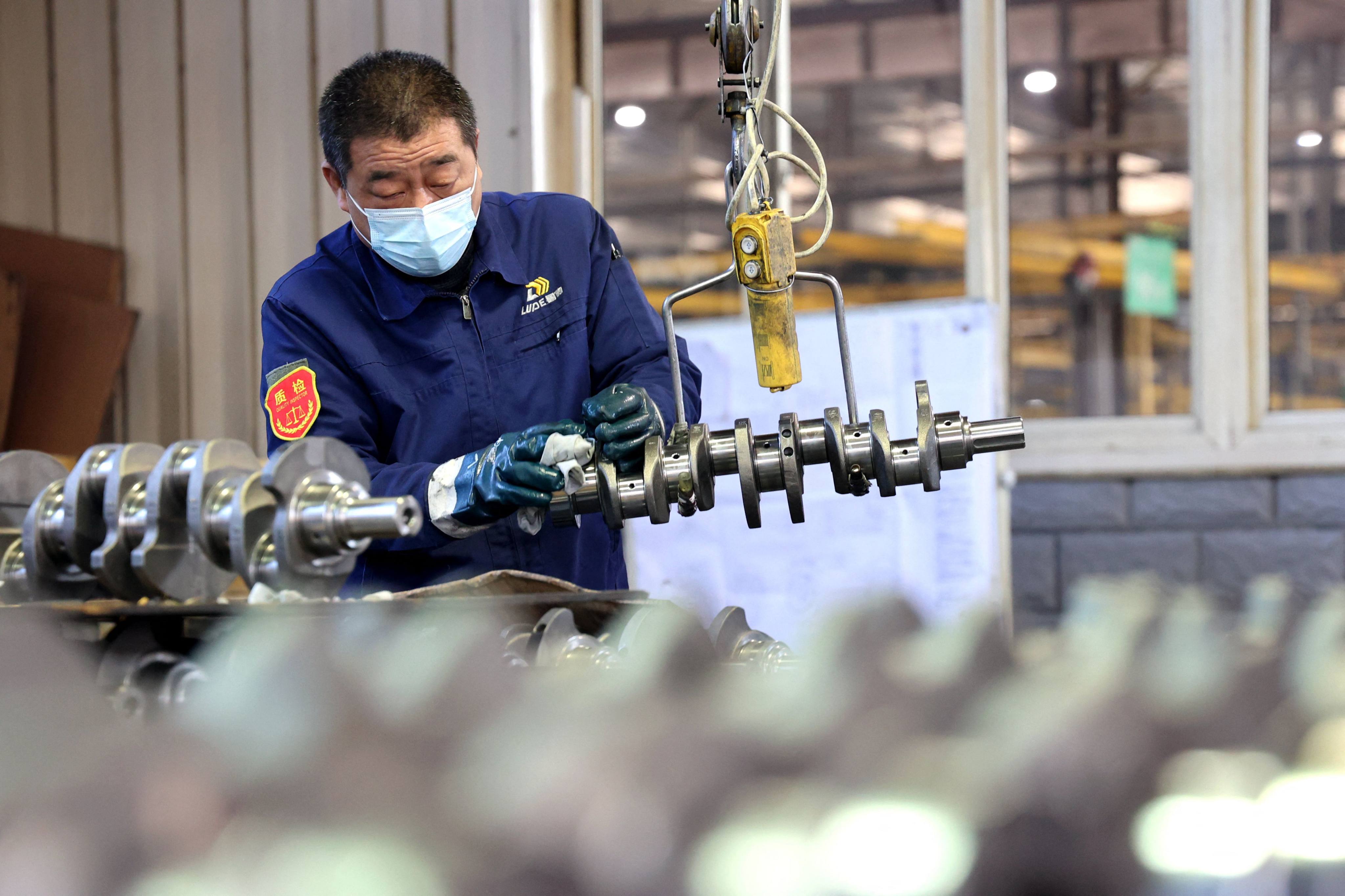 A quality inspector checks crankshafts at a factory which produces the mechanical component for both the domestic market and export in Binzhou in China’s eastern Shandong province. Photo: AFP