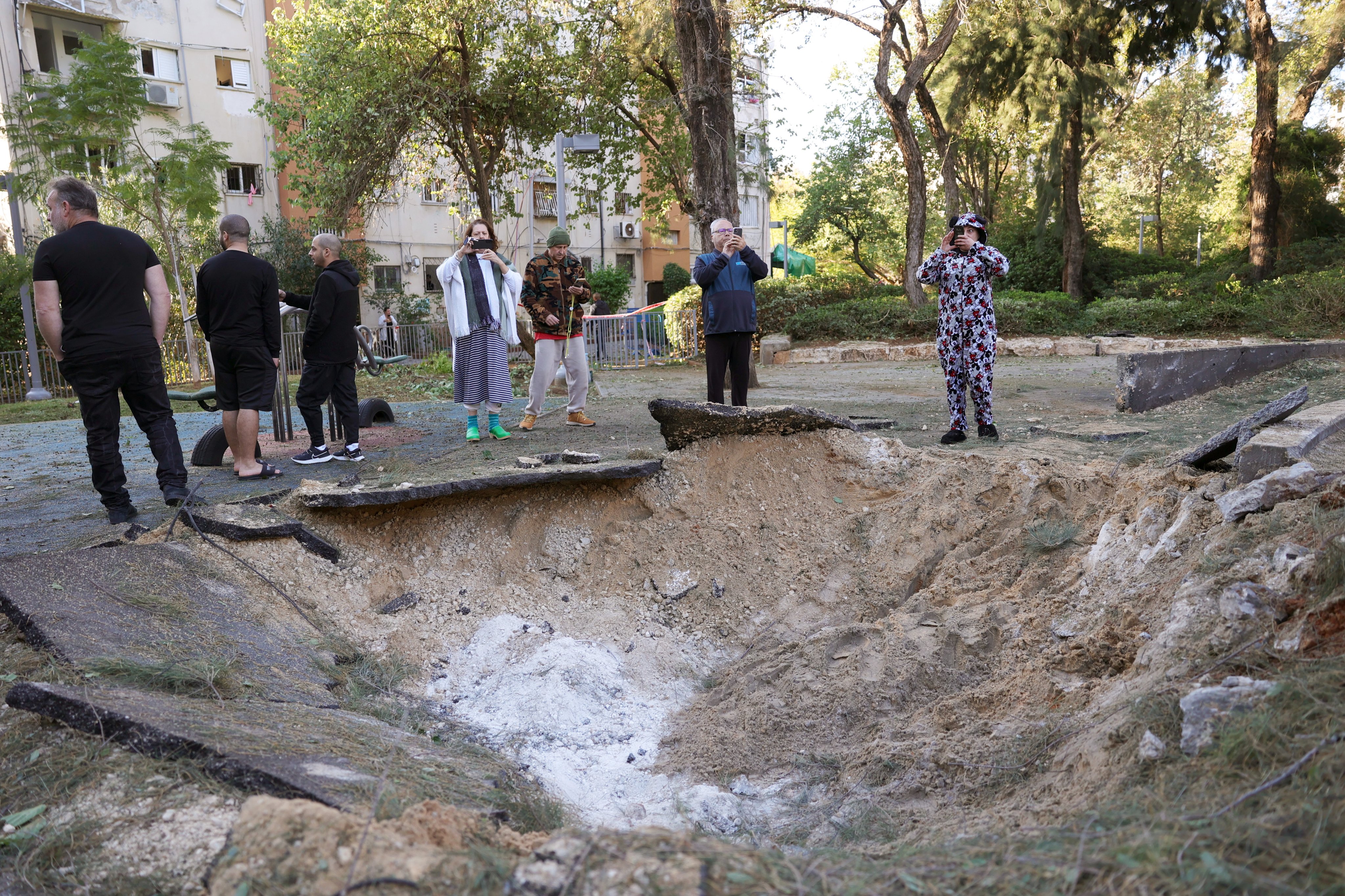 Residents stand near the scene of a missile attack in Tel Aviv, after a missile fired from Yemen hit a playground in Tel Aviv. Photo: EPA-EFE