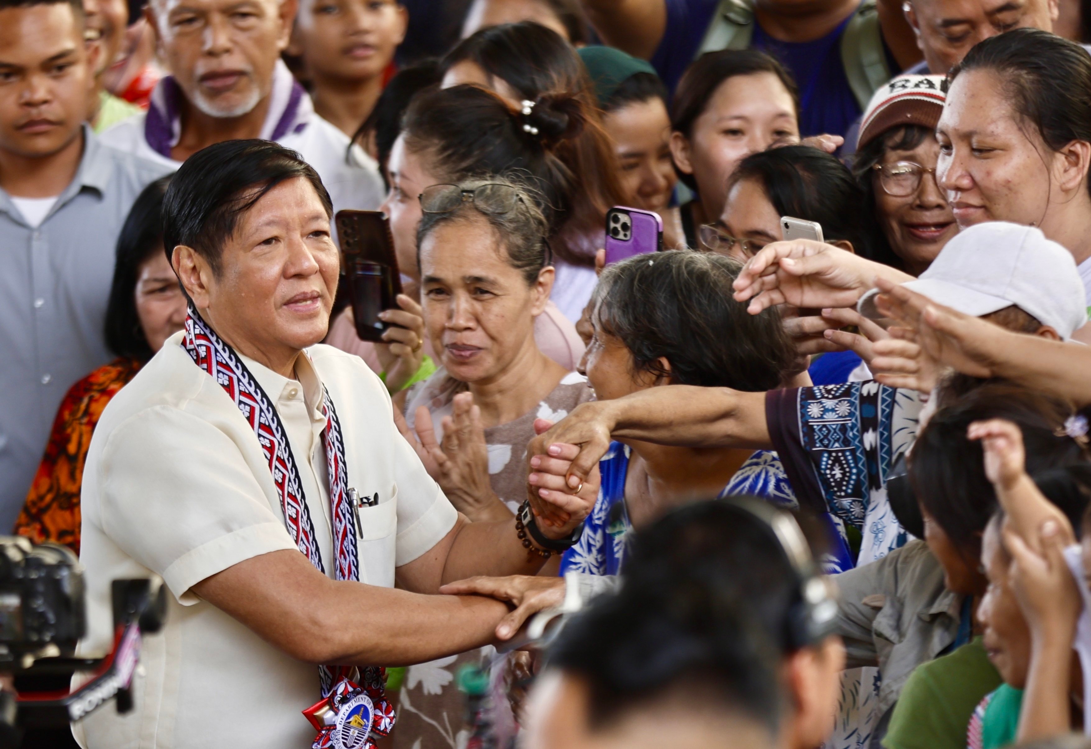 Philippine President Ferdinand Marcos Jnr shakes hands with residents during the distribution of food aid in Manila on December 14. Photo: EPA-EFE