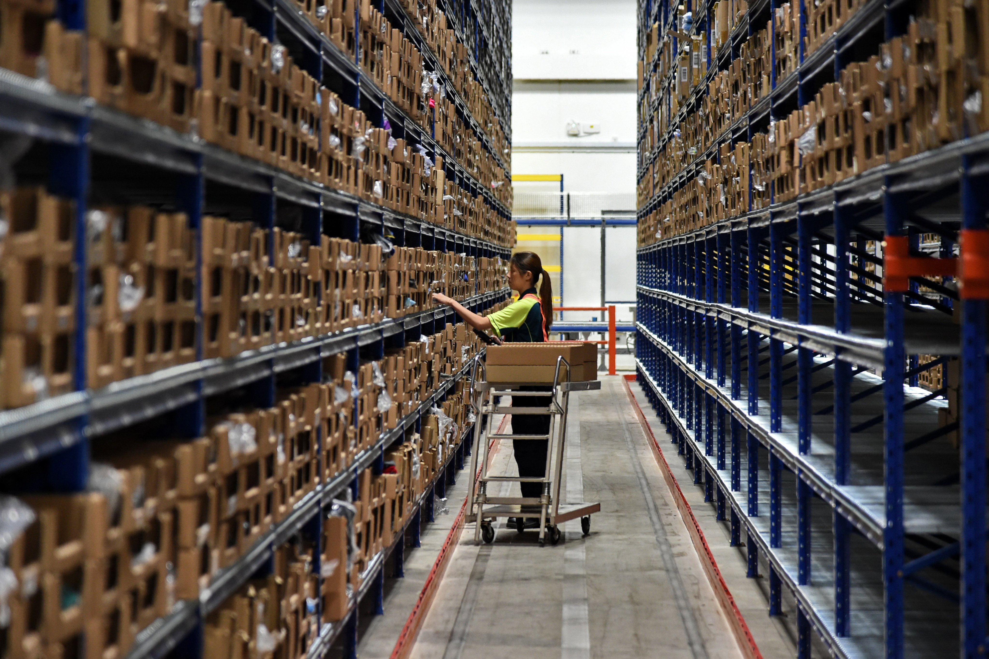 An employee picks up orders from the shelves in a warehouse at SingPost’s logistics hub in Singapore. SingPost’s CEO and executives were fired following allegations related to the firm’s international e-commerce logistics business. Photo: AFP