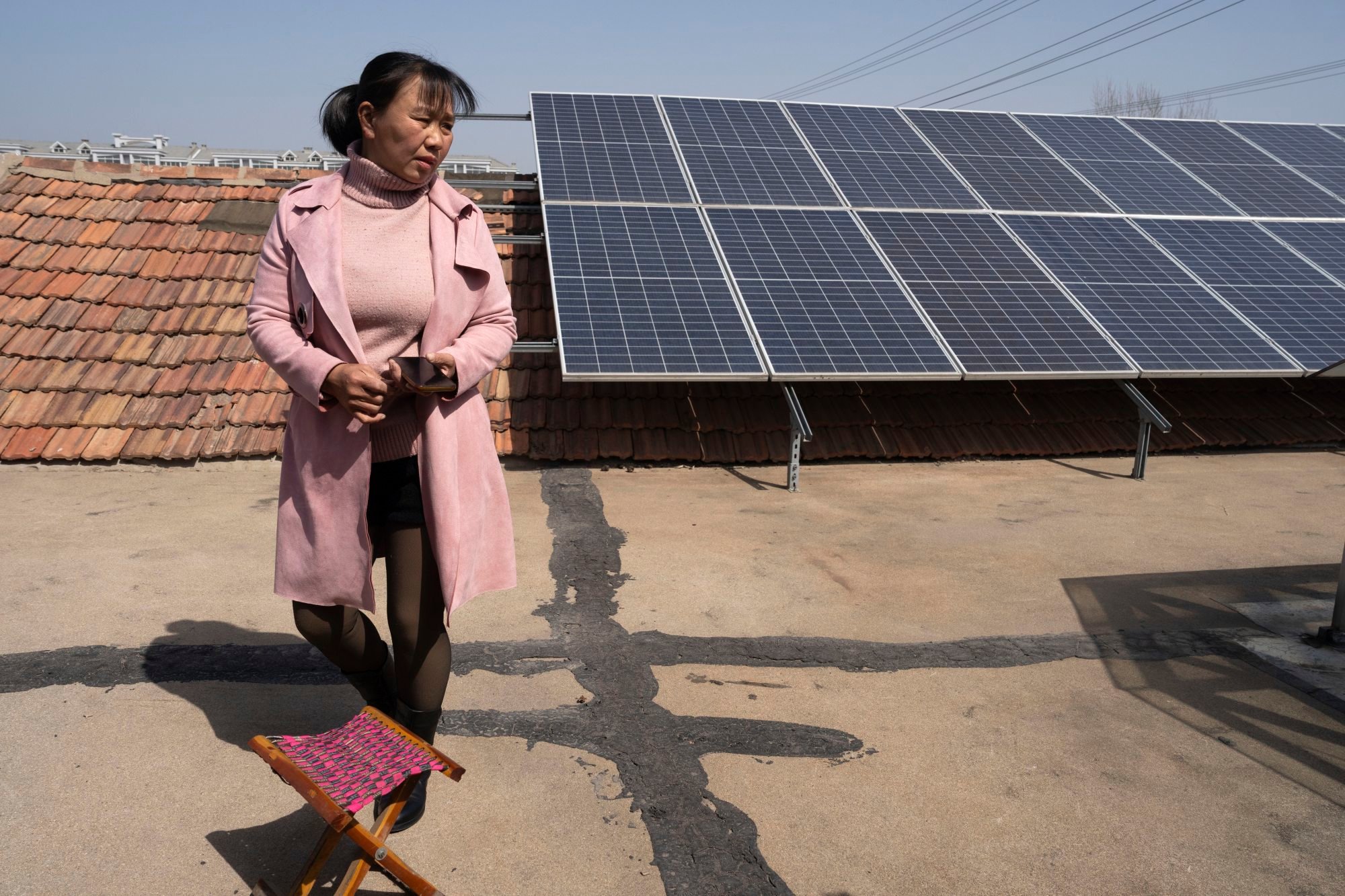 Farmer Shi Mei stands beside solar panels on her rooftop on the rural outskirts of Jinan, Shandong province, in March. Photo: AP Farmer Shi Mei stands beside solar panels on her rooftop on the rural outskirts of Jinan, Shandong province, in March. Photo: AP