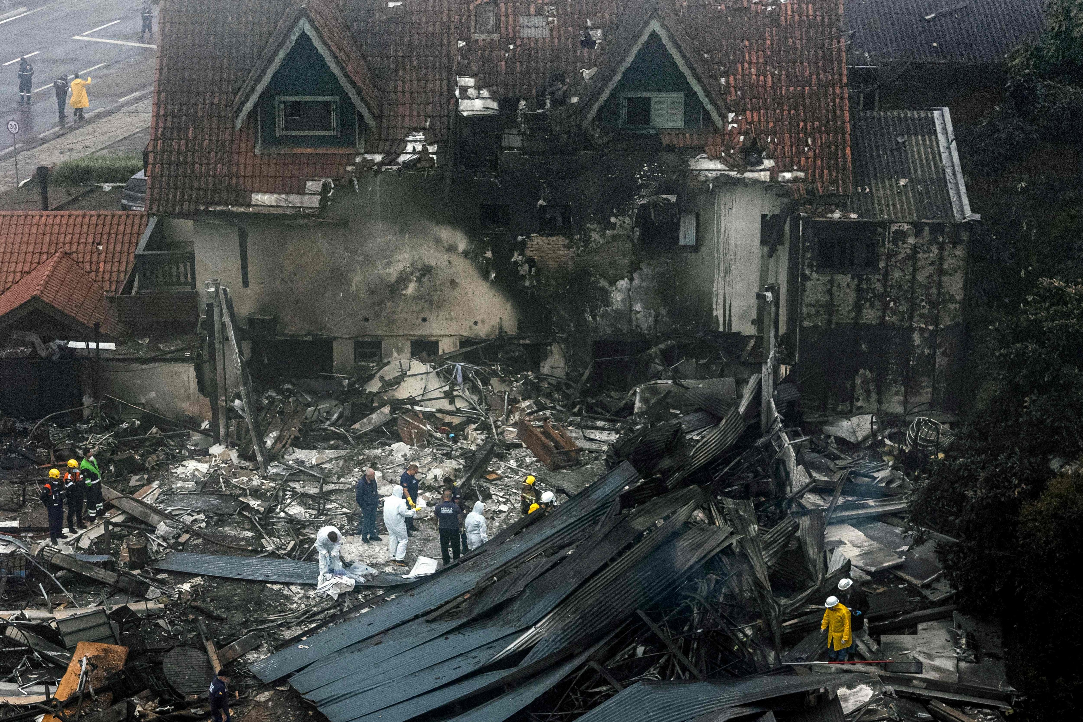 Firefighters and other rescue teams at the scene of the plane crash. Photo: : Mateus Bruxel, Agência RBS via AFP