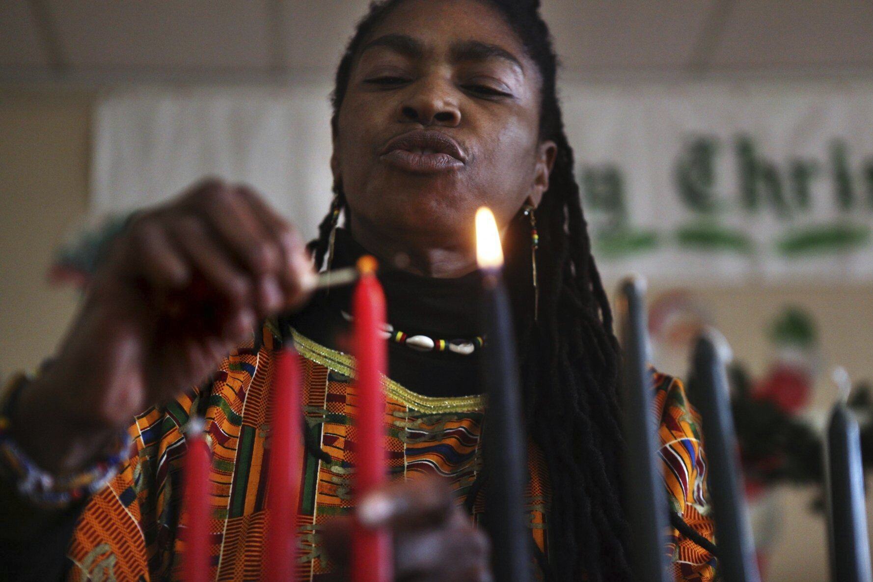 Ayodele Kofie lights the first two candles of Kwanzaa, representing the days for unity and self-determination. Photo: AP