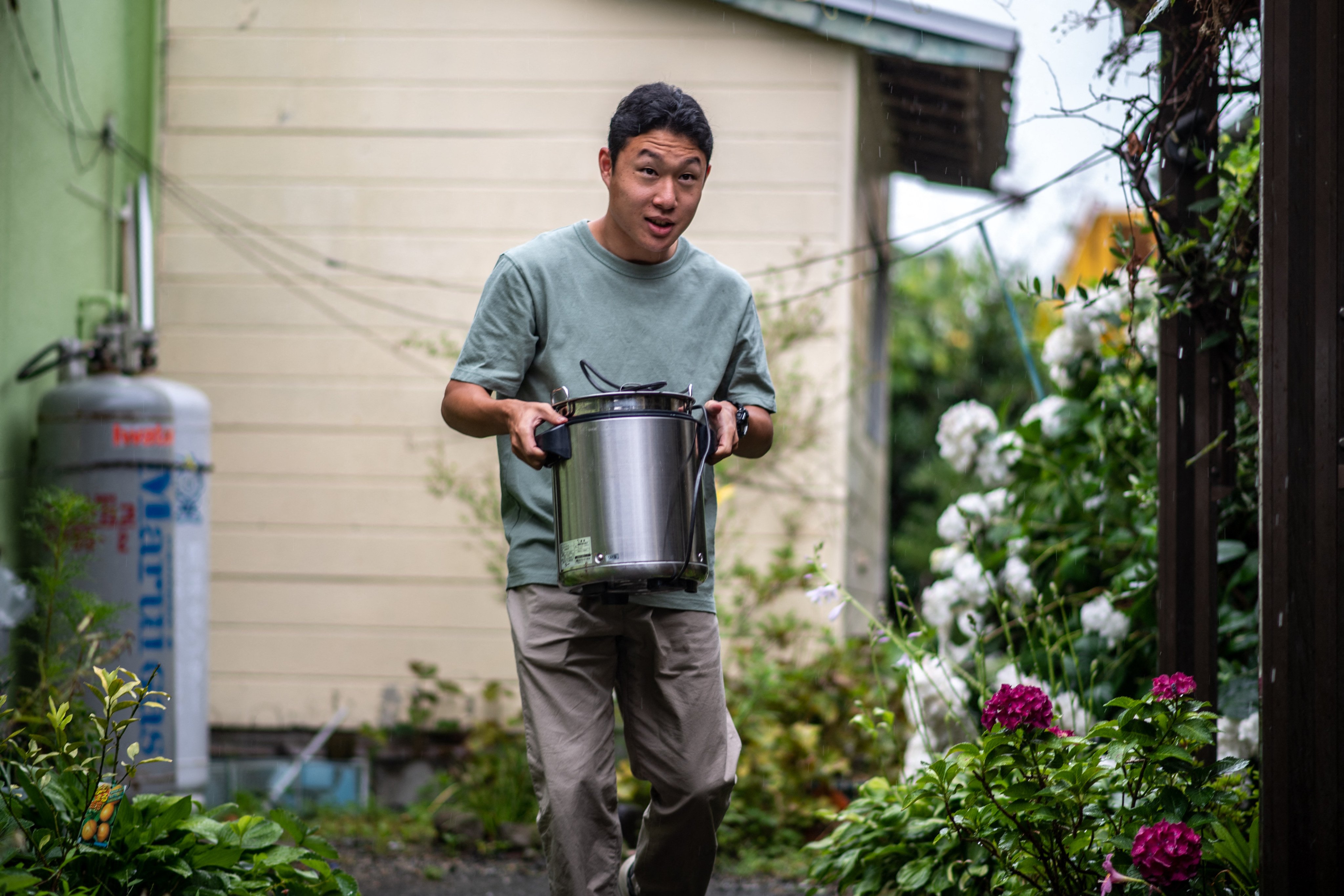 Koichi Miyatsu carries a pot as he prepares to transport meals from his home to a church as part of a monthly charity event for underprivileged children in Kumamoto, Japan, on March 11, 2022. Photo: AFP