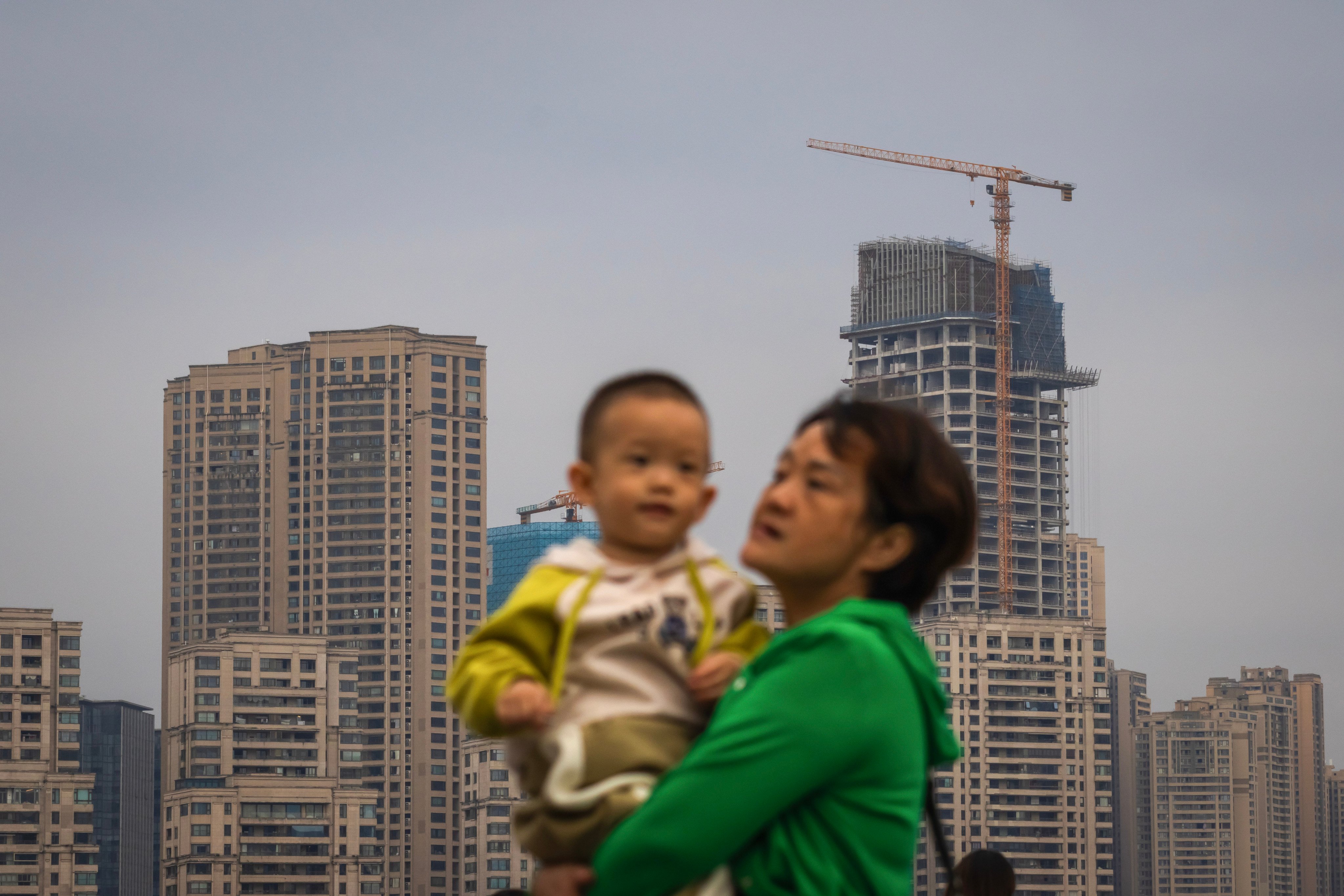 A mother held her child with high-rise buildings and a construction site in the background in Chongqing. Photo: Getty Images