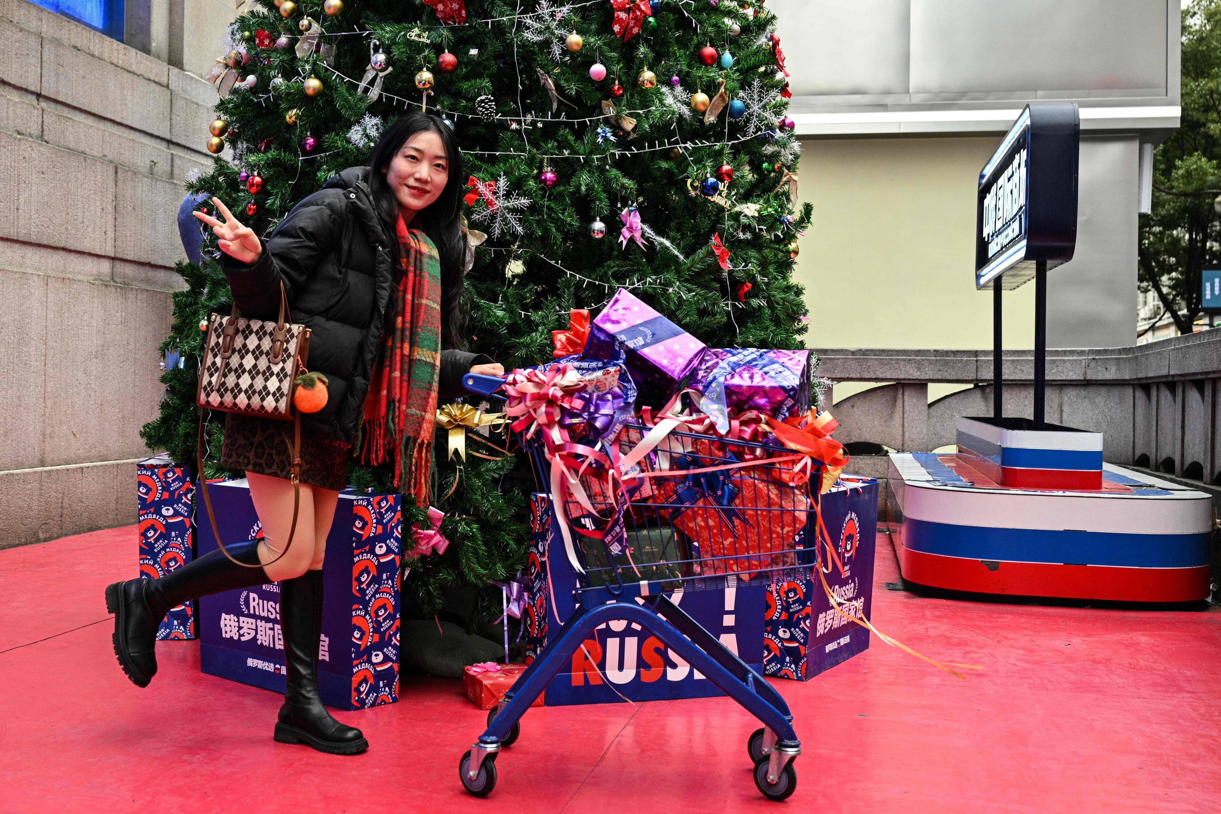 A woman poses next to a Christmas tree in a shop selling Russian products in Wuhan, Hubei province, on Sunday. Photo: AFP