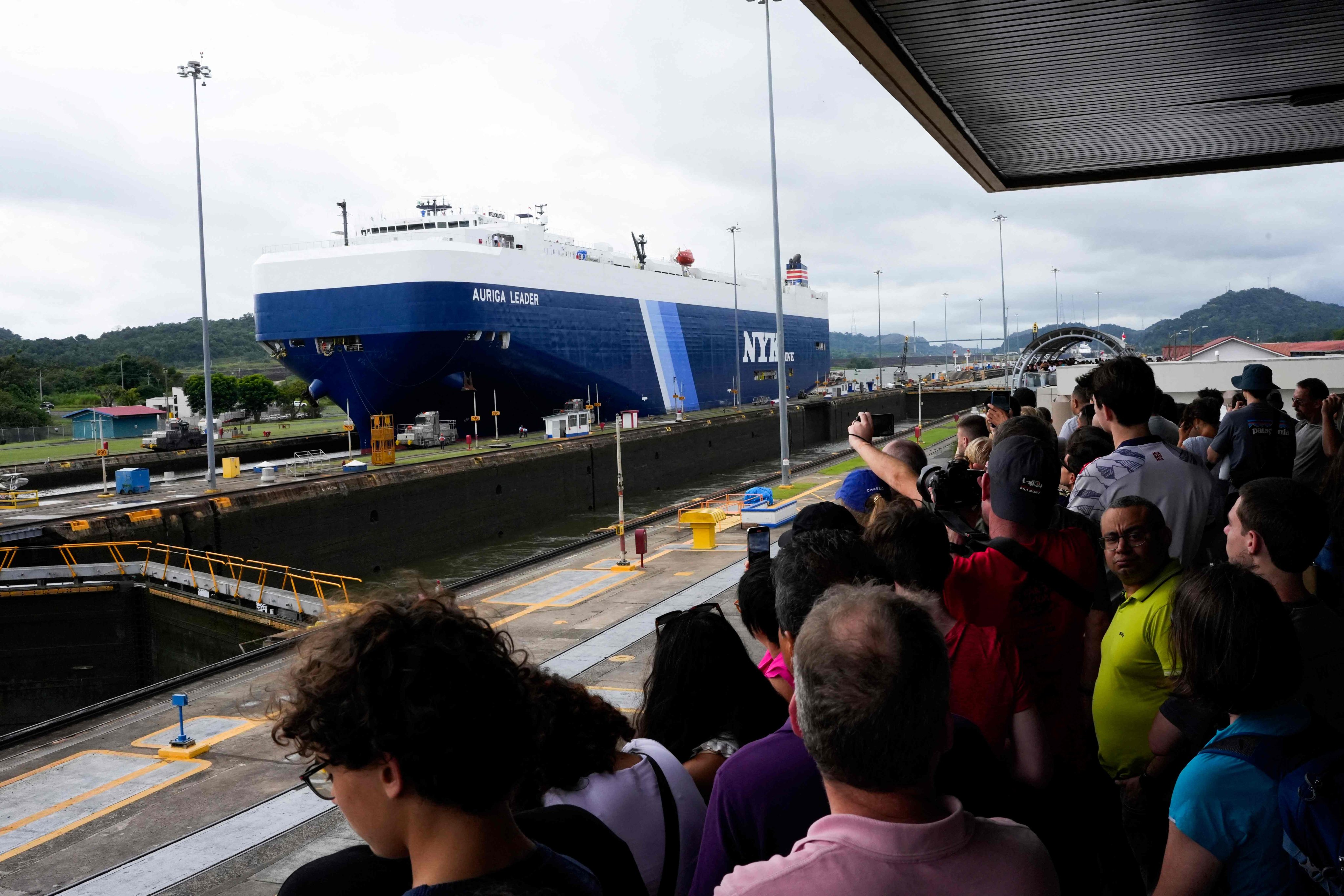 Tourists watch a cargo ship transit through the Panama Canal in Panama City on December 23. Photo: AFP