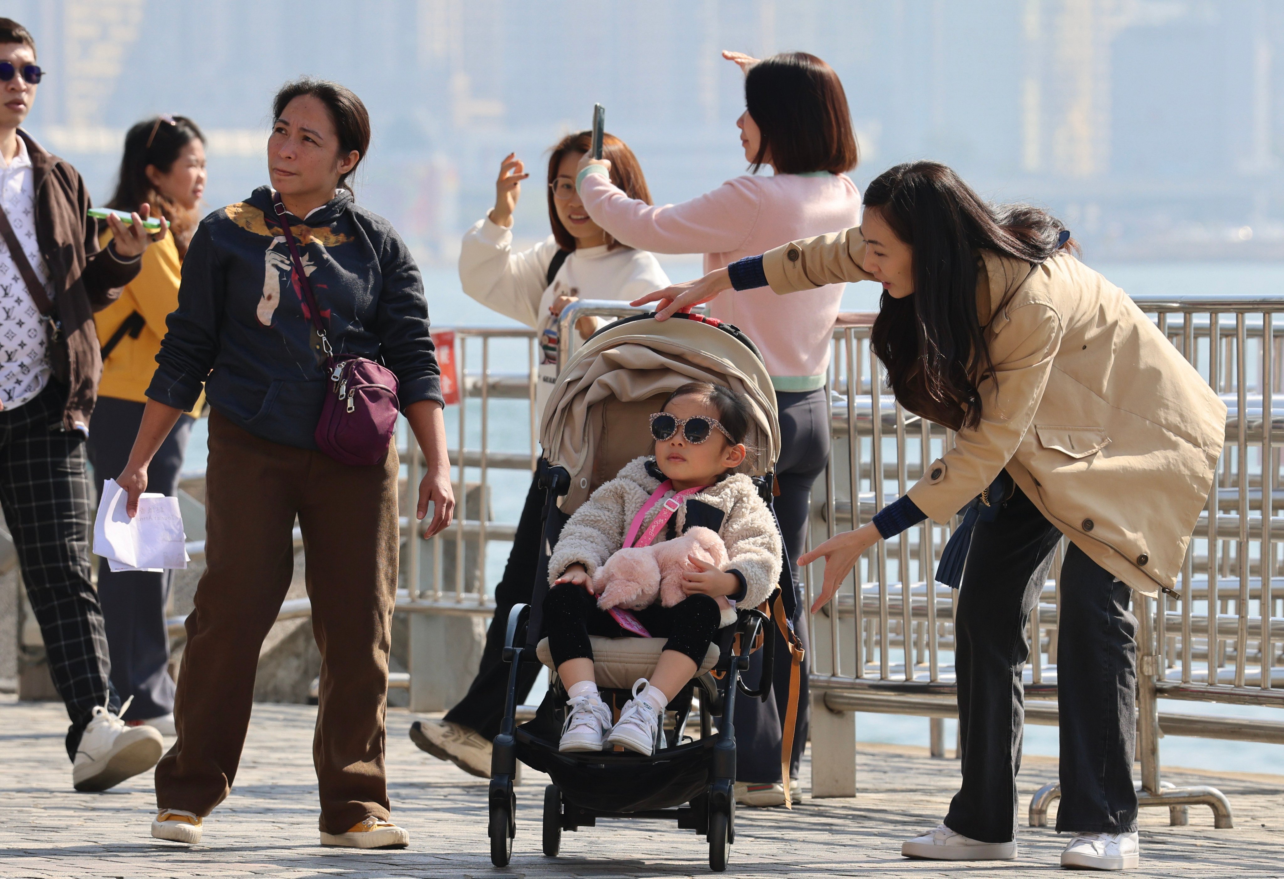 People gather along the Tsim Sha Tsui waterfront. With the monsoon moderating early next week, temperatures are due to climb back up to between 16 and 21 degrees Celsius. Photo: Jelly Tse