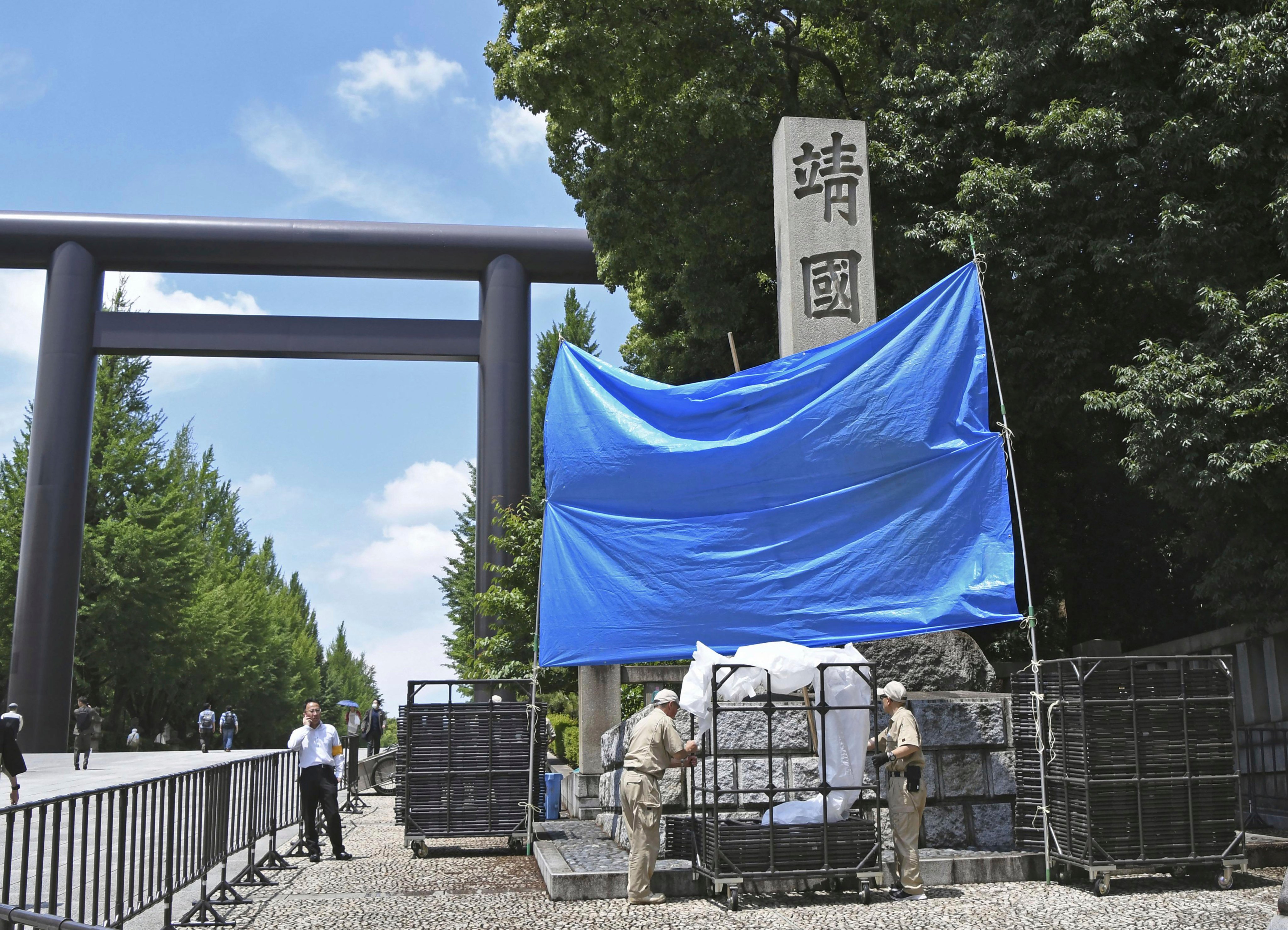 Workers prepare to remove graffiti on a pillar at Yasukuni Shrine in Tokyo in June. Photo: Kyodo via AP