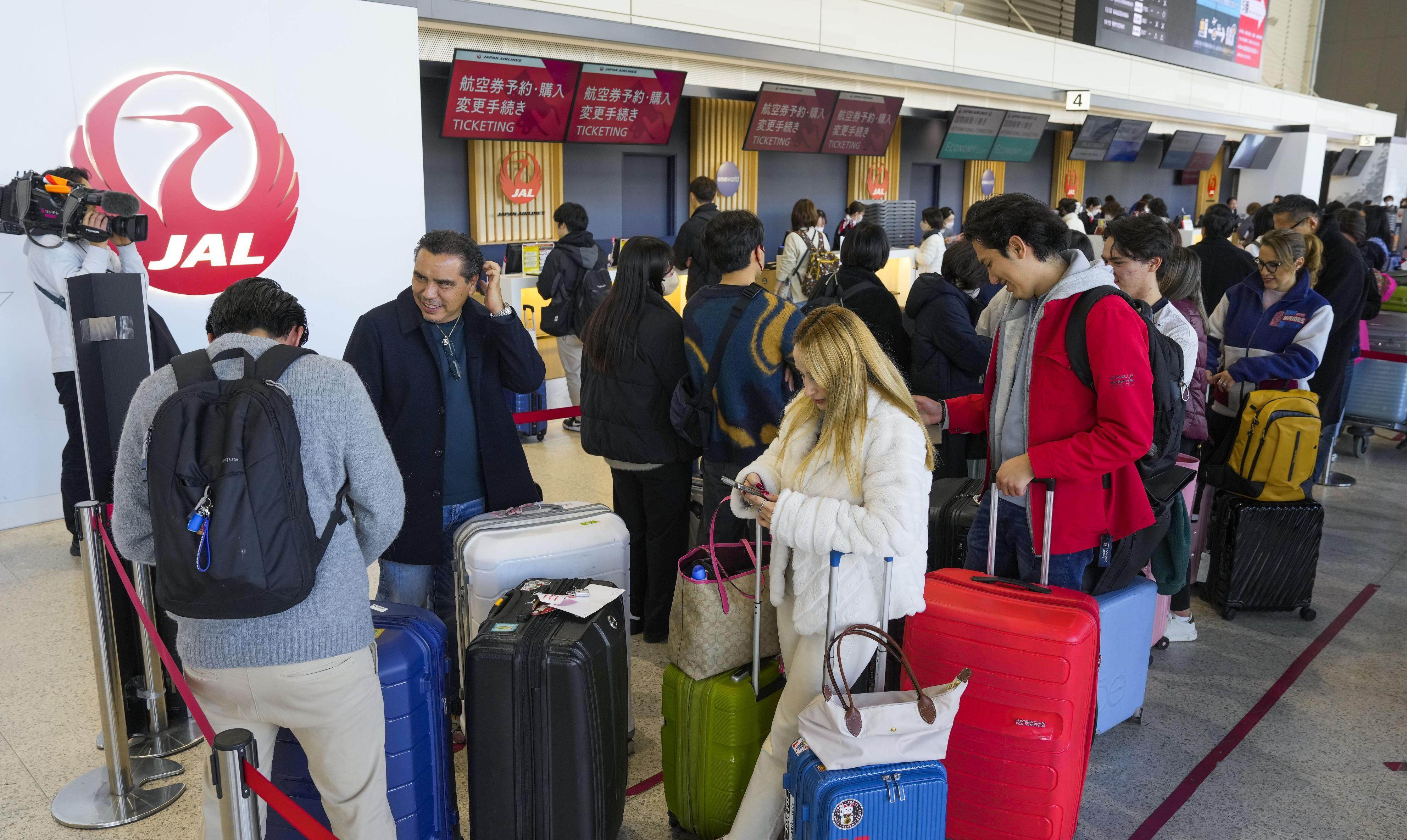 Passengers wait at a Japan Airlines check-in counter at Osaka airport on Thursday. Photo: Kyodo