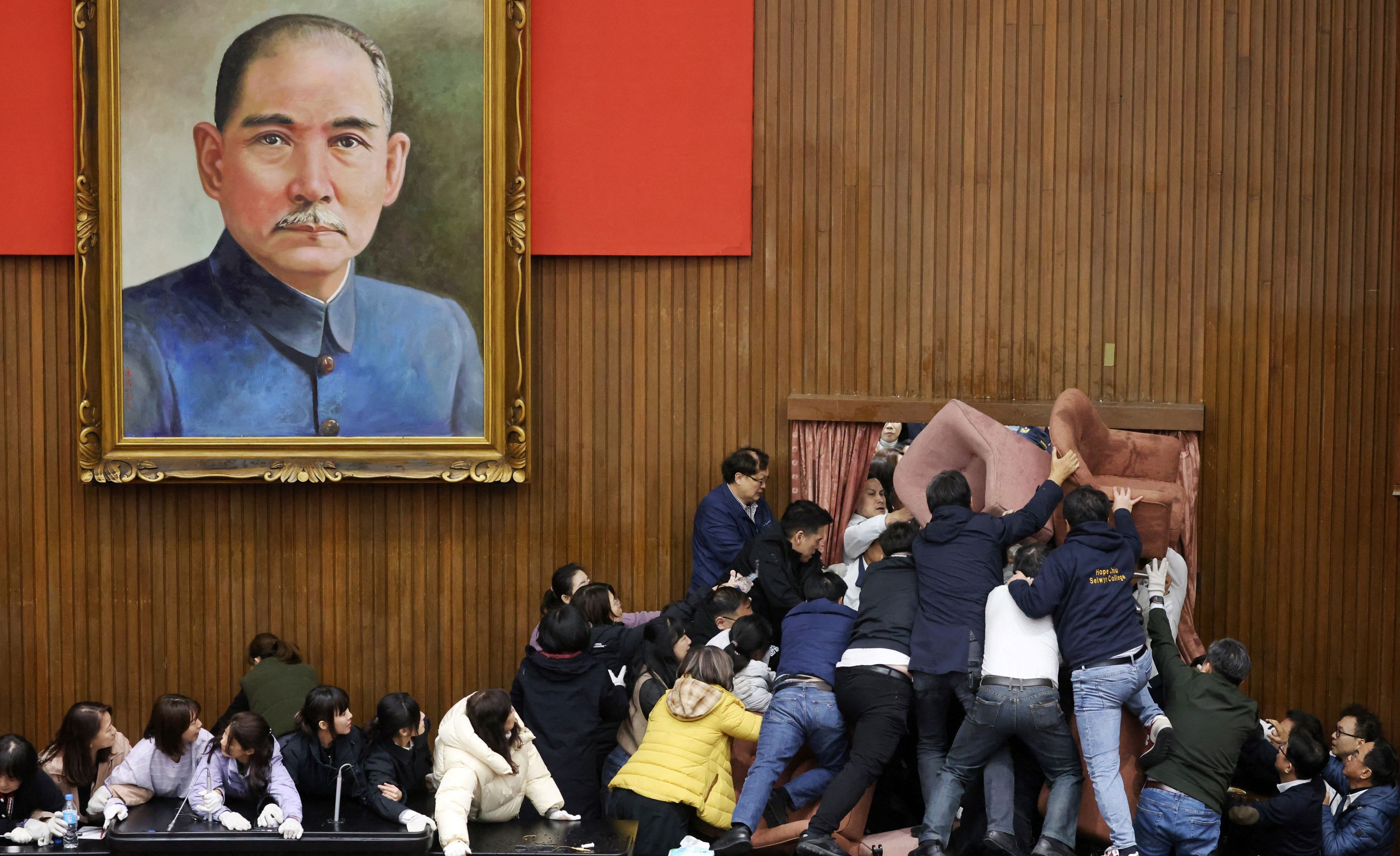 Opposition Kuomintang lawmakers (in white) trying to enter the Legislative Yuan, which the ruling  Democratic Progressive Party (DPP) has barricaded with chairs, on December 20. Photo: AFP