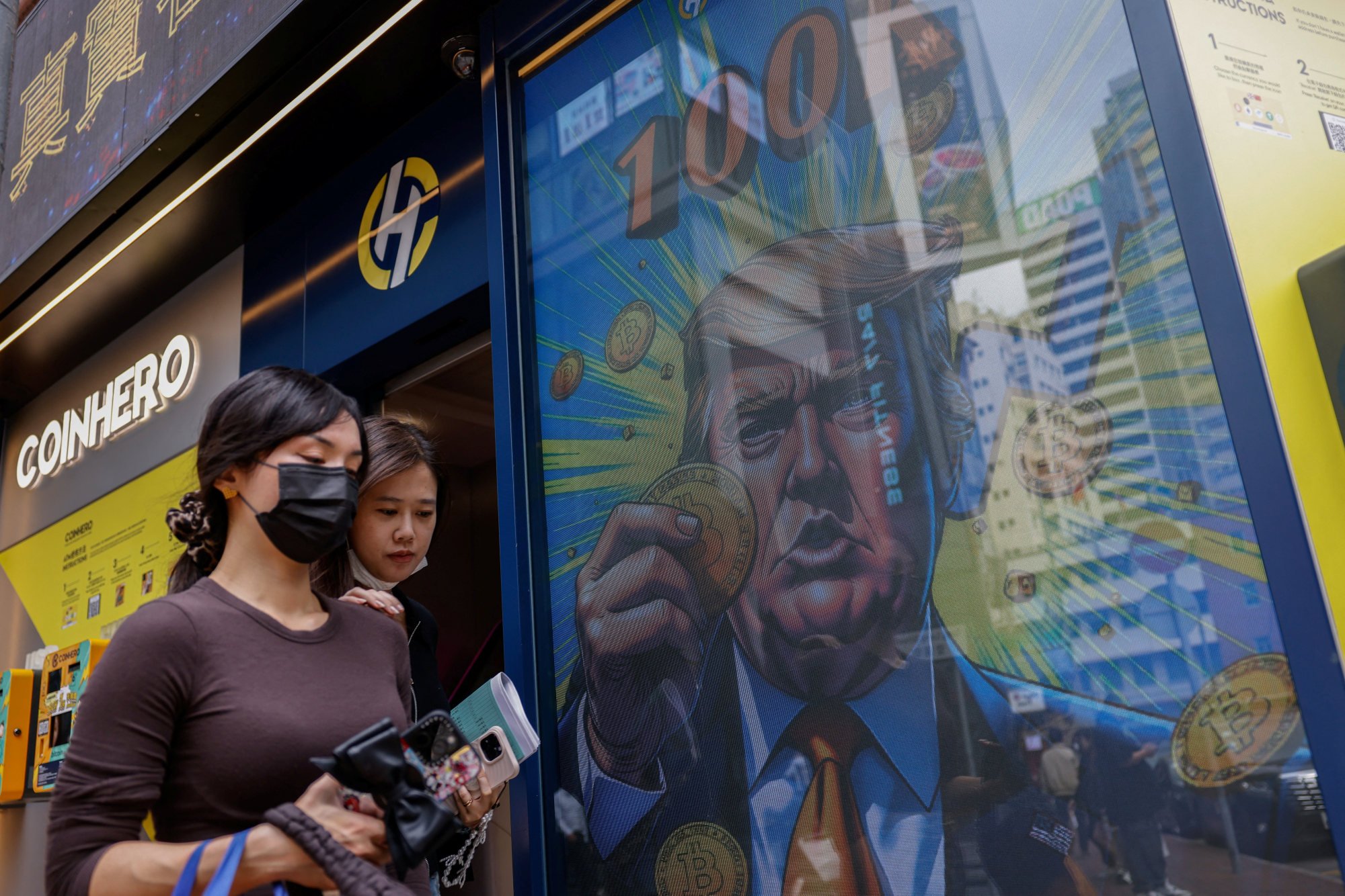 An illustration that features Donald Trump holding a bitcoin is displayed outside a cryptocurrency exchange store in Hong Kong. Photo: Reuters