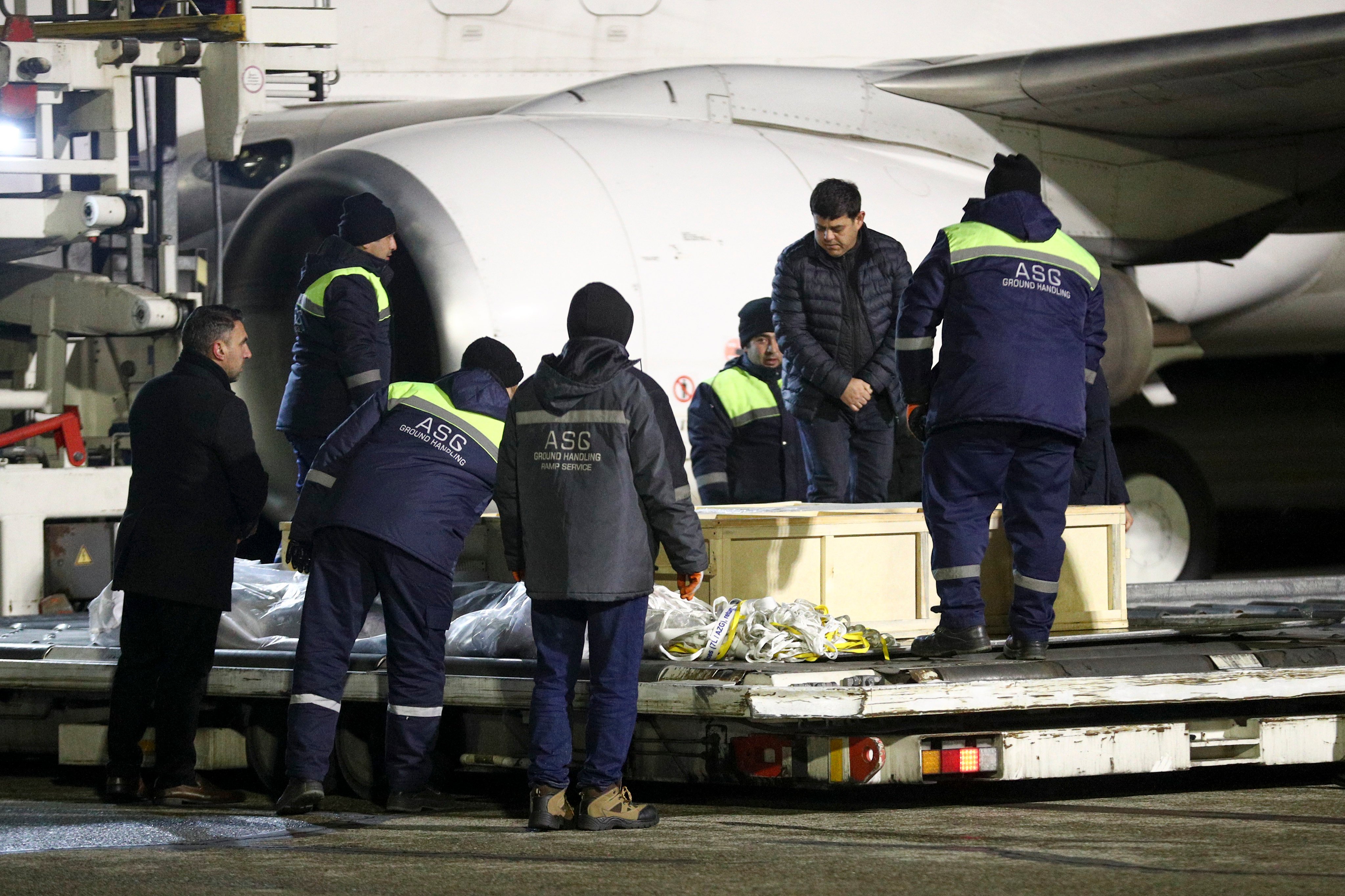 Workers remove coffins of victims from a plane at Heydar Aliyev International Airport outside Baku, Azerbaijan on Saturday after the Azerbaijan Airlines crash near Aktau, Kazakhstan. Photo: AP