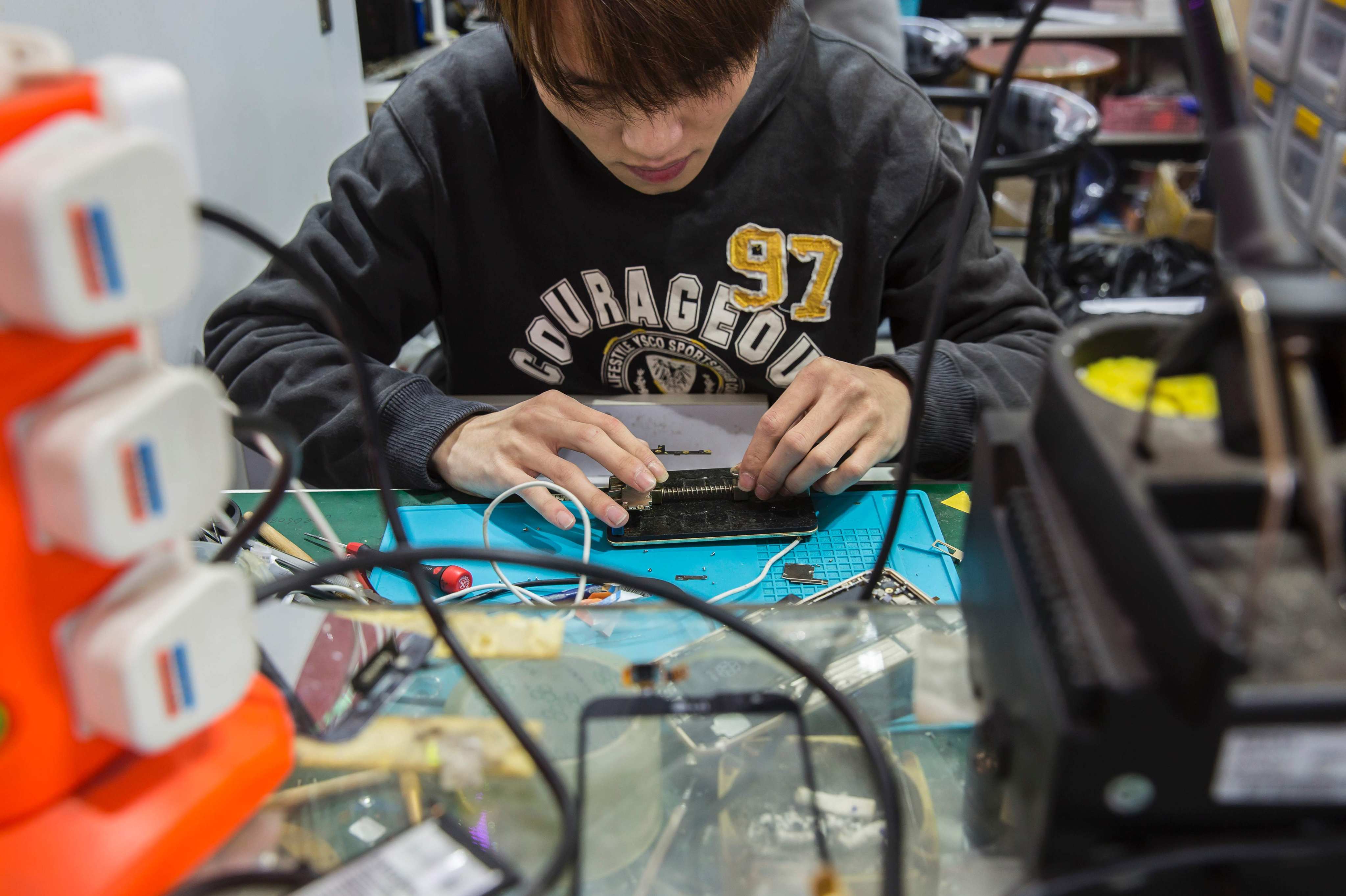 A worker repairs a mobile phone in a shop in Sham Shui Po, Hong Kong, in 2017. Photo: AFP