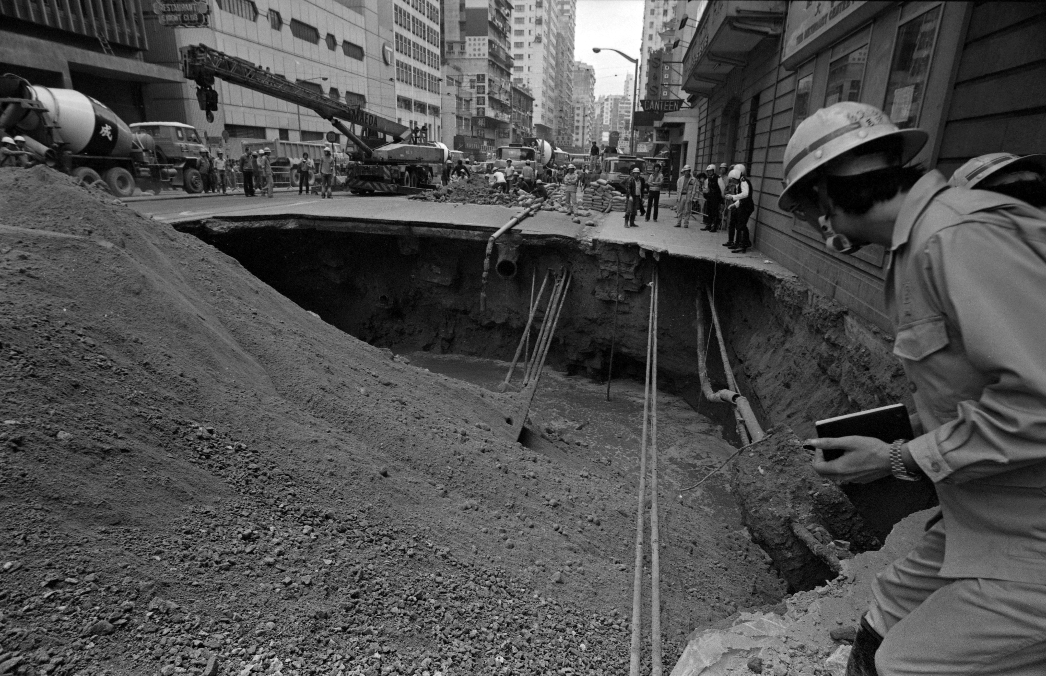 A worker inspects a gaping hole caused by a road collapse on Hennessy Road, Hong Kong, in 1983. Photo: Sunny Lee