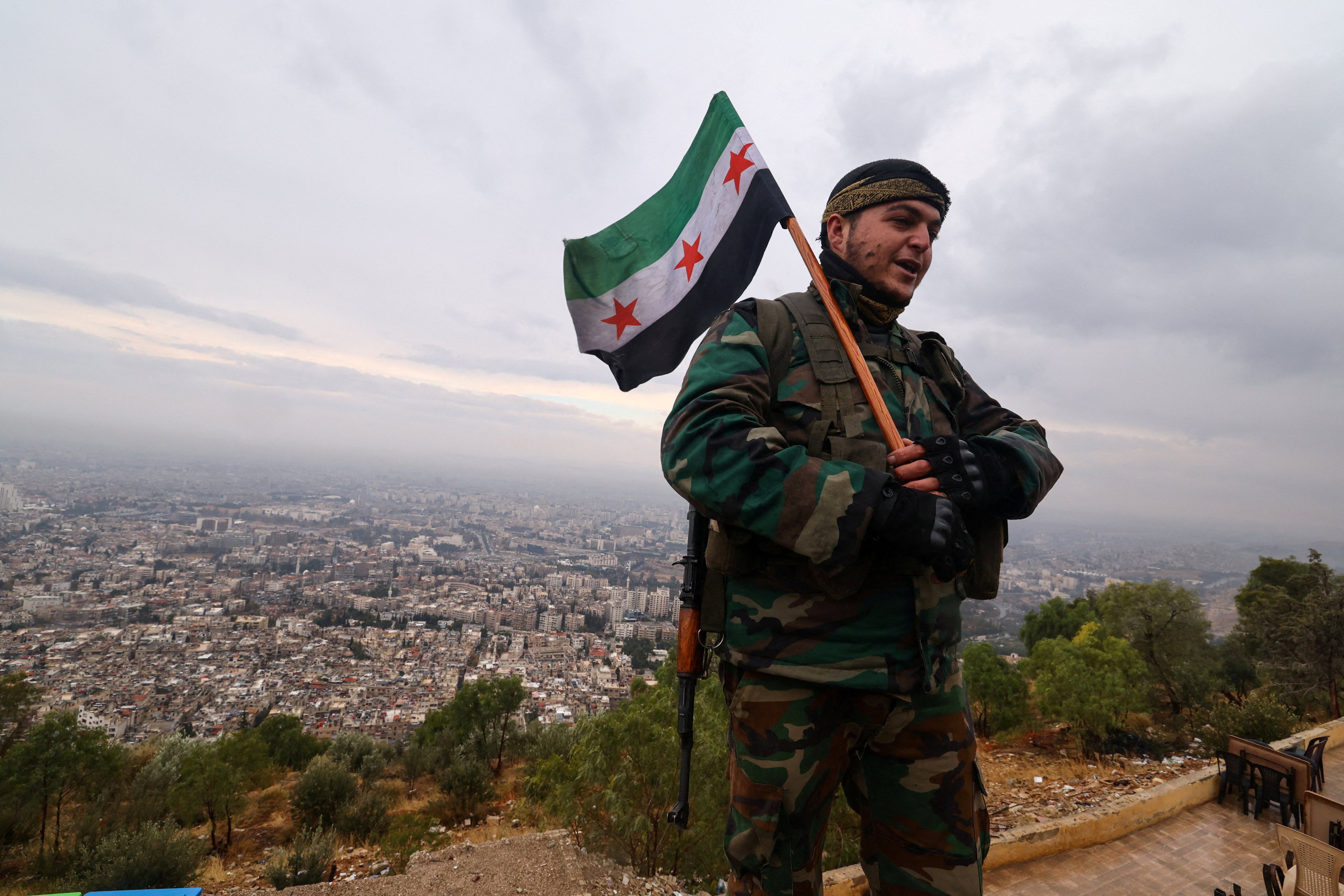 A fighter holds the flag adopted by Syria’s new government, as he visits Mount Qasioun, which was off-limits during the civil war, after the ousting of president Bashar al-Assad, in Damascus, Syria, on December 29. Photo: Reuters