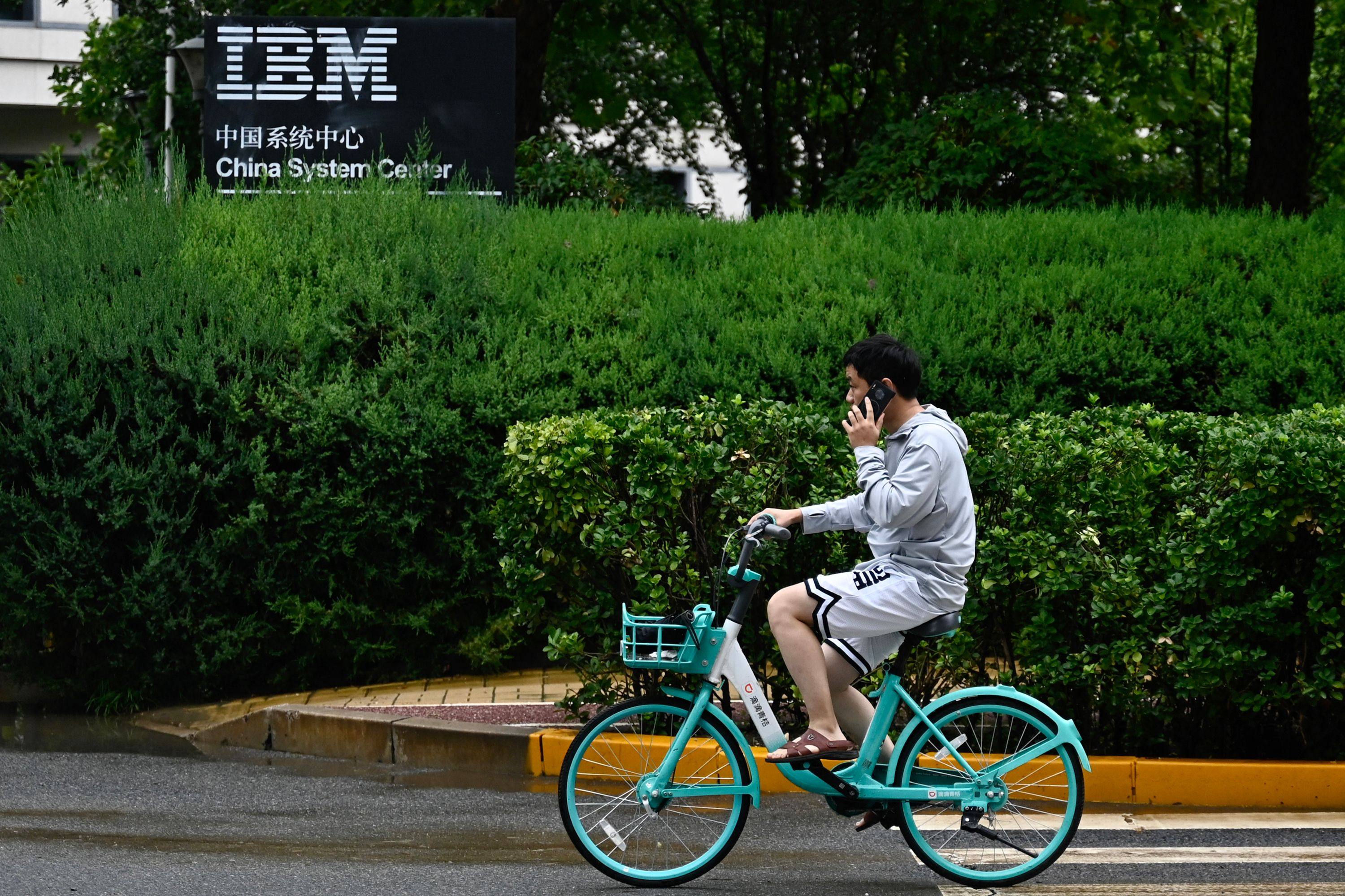 The IBM logo is seen as a person cycles past the company’s China System Center building in Beijing on August 26, 2024. Photo: AFP