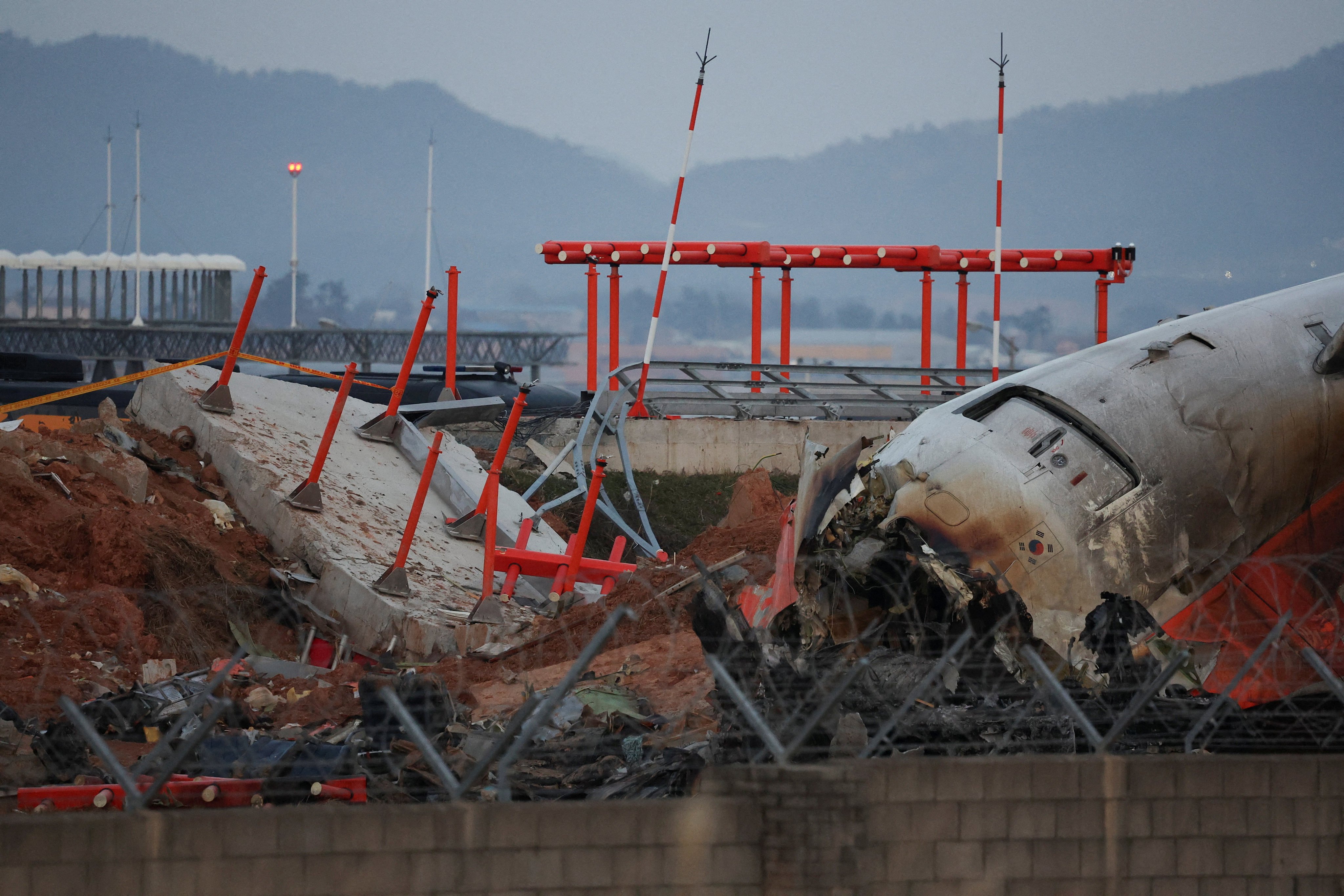 The wreckage of the Jeju Air plane lies near a concrete structure it crashed into at Muan airport. Photo: Reuters