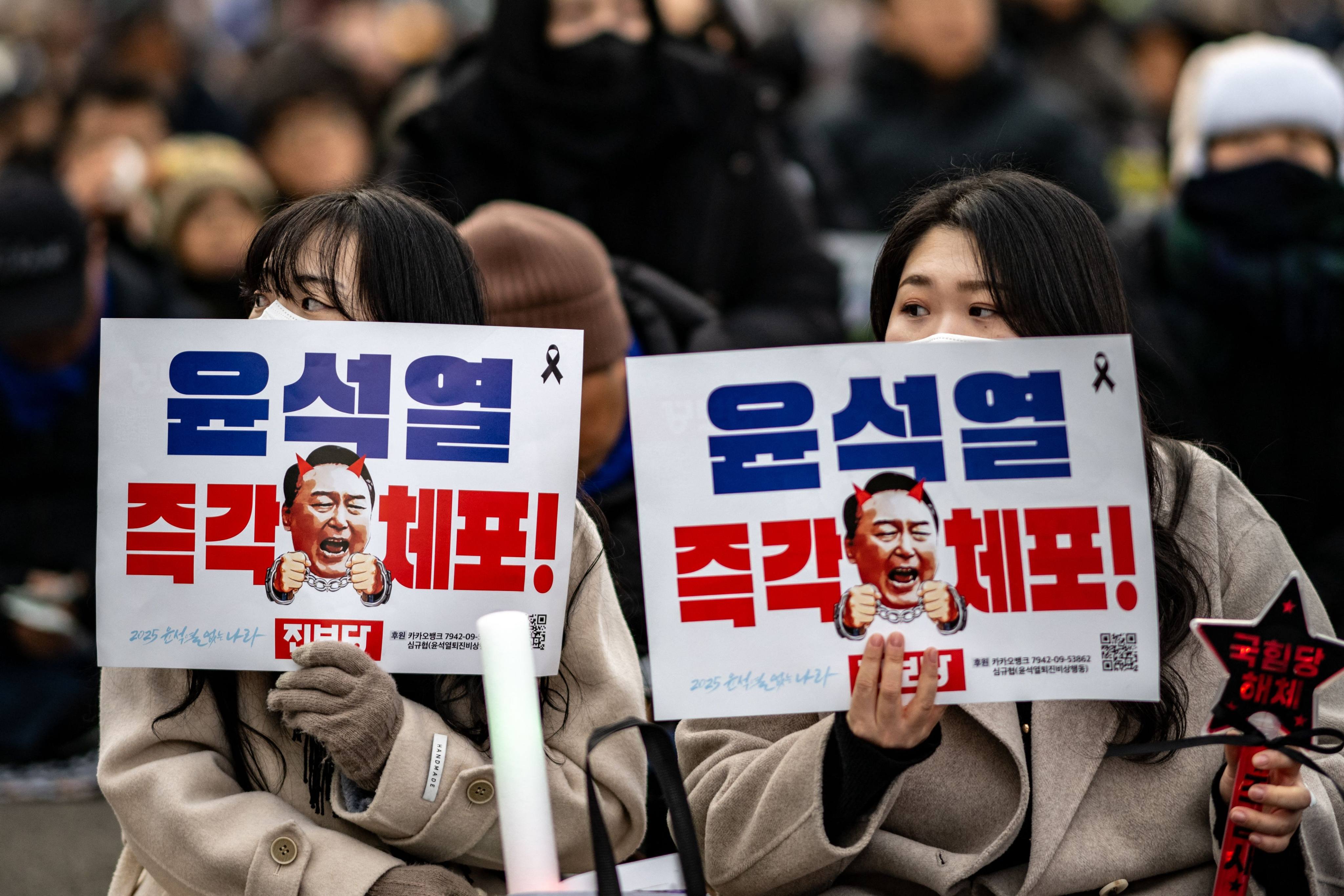 People holding placards reading “Arrest Yoon Suk Yeol immediately” during a protest in Seoul on Saturday. Photo: AFP