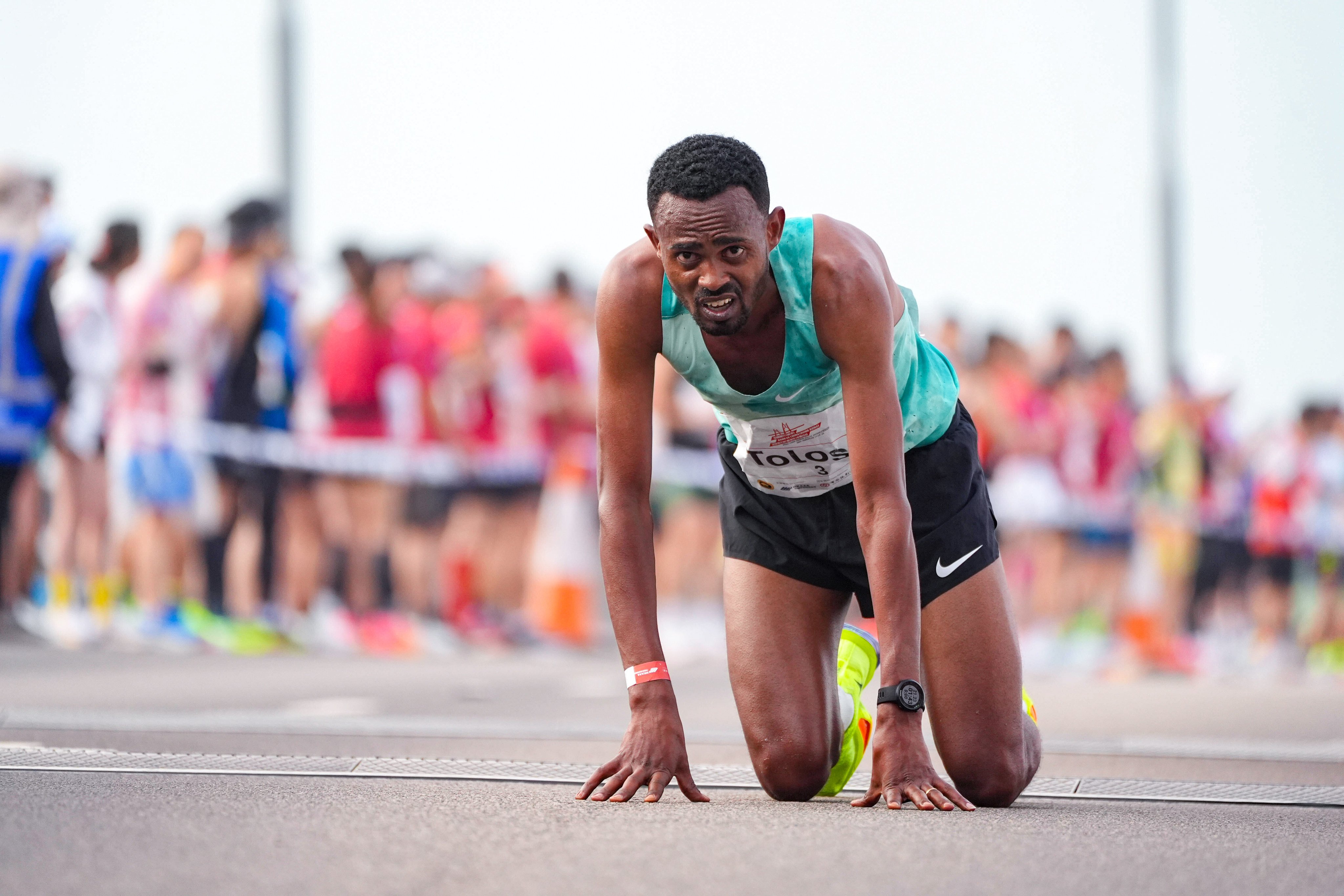 Ethiopia’s Milkesa Mengesha is on his knees after winning the Hong Kong-Zhuhai-Macau Bridge Half Marathon. Photo: Eugene Lee