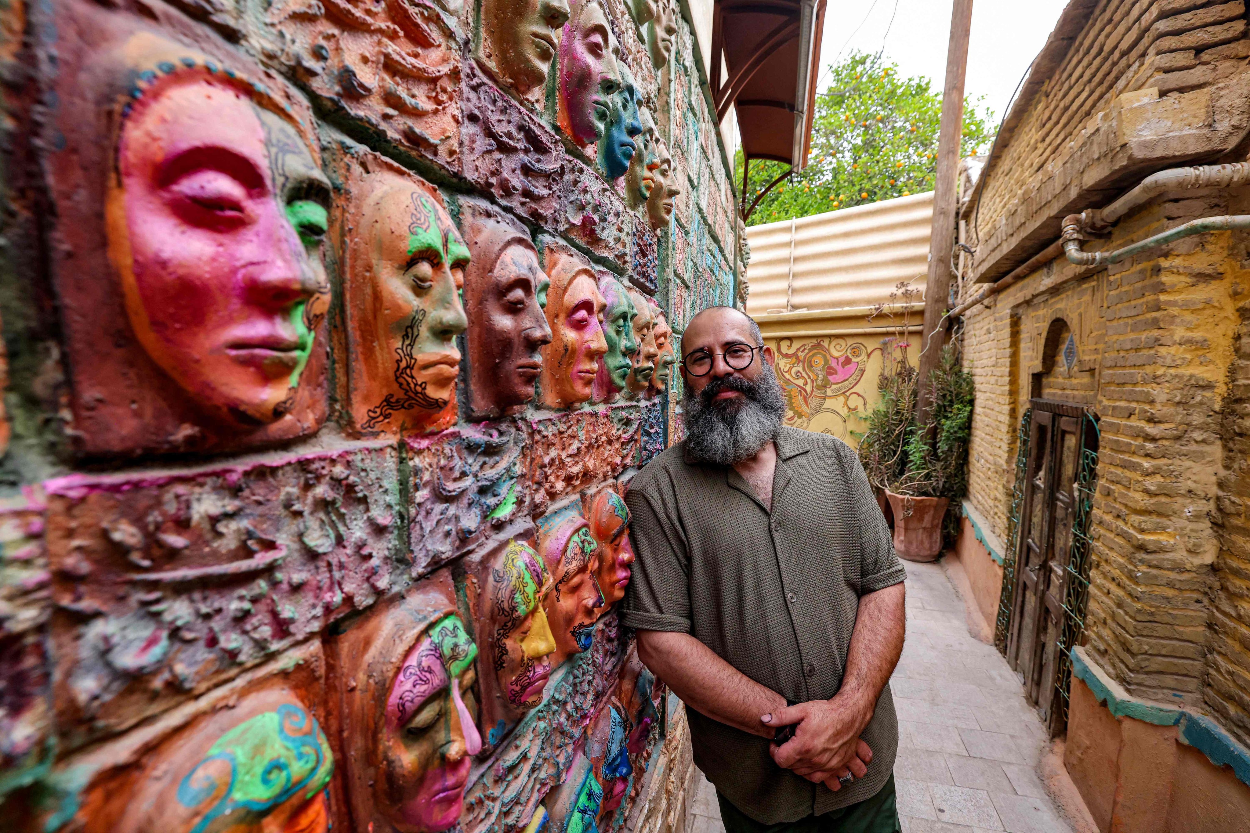 Iranian artist Adel Yazdi stands next to some of his high reliefs in an alley in Narenjestan, Shiraz, Iran on May 14, 2024. Photo: AFP