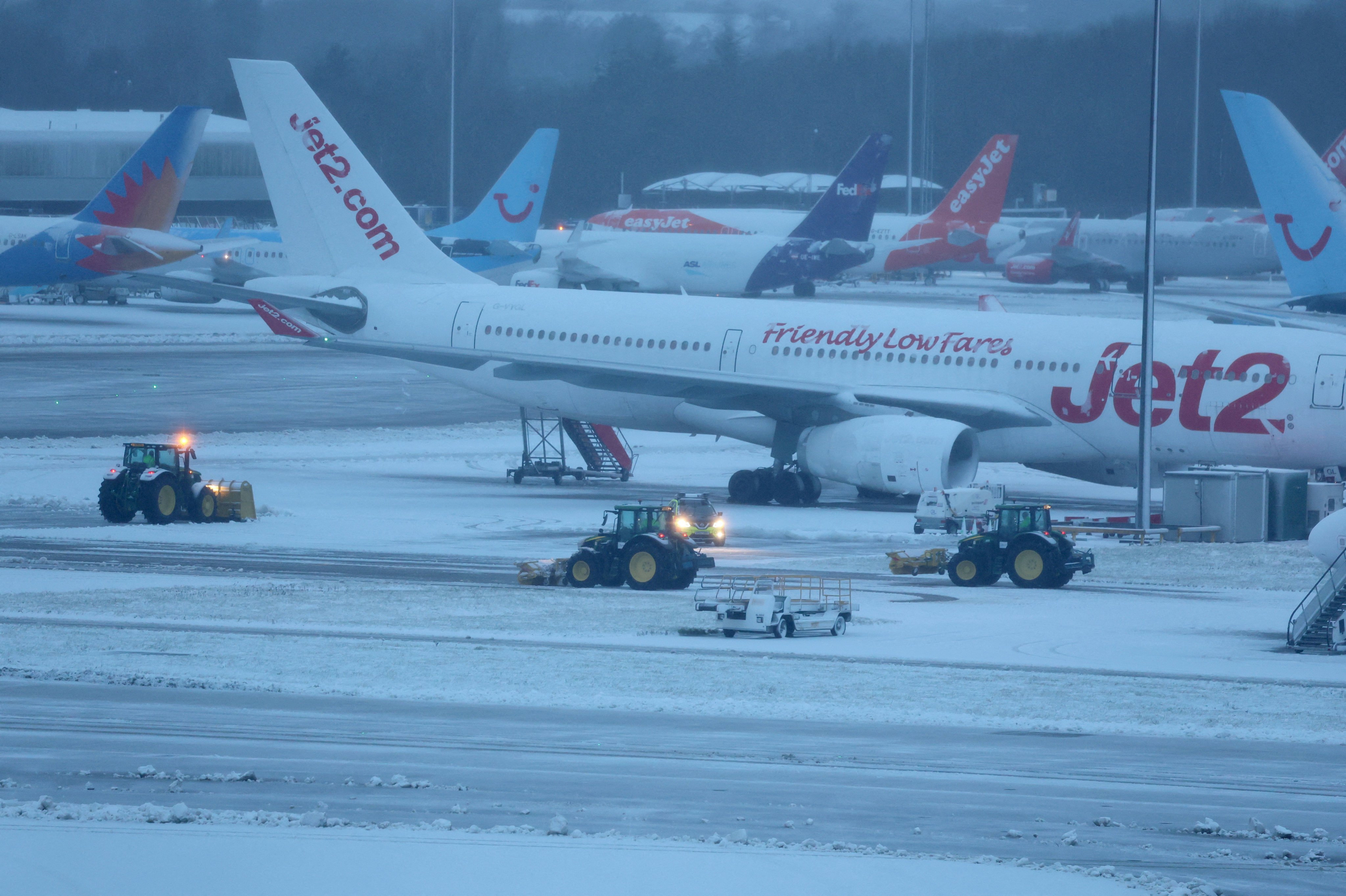 Staff use tractors to help clear snow from around aircraft at Manchester Airport in Manchester, Britain. Photo: Reuters